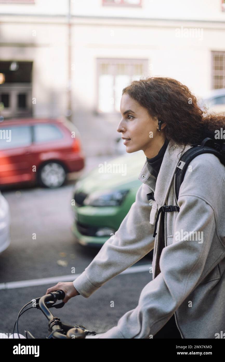 Female architect commuting through bicycle on road in city Stock Photo