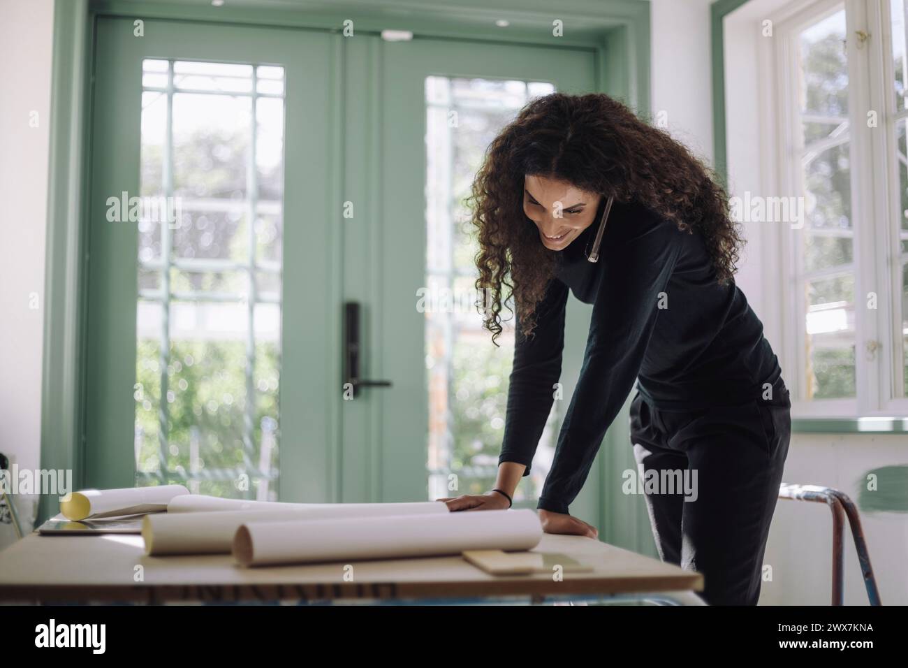 Smiling female construction engineer doing multi-tasking while working at under construction apartment Stock Photo