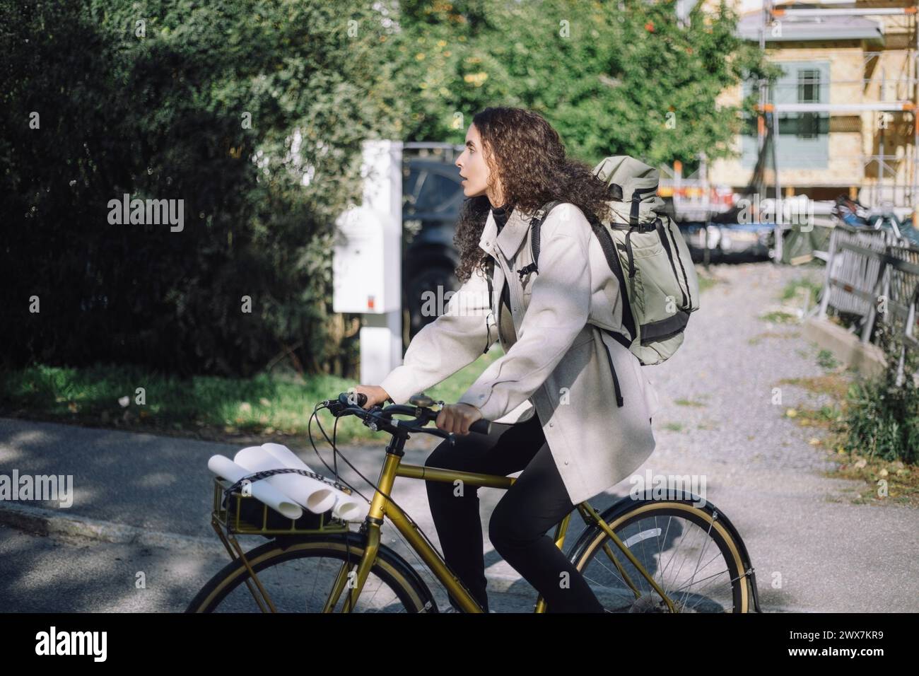 Female designer professional with backpack commuting through cycle at street Stock Photo