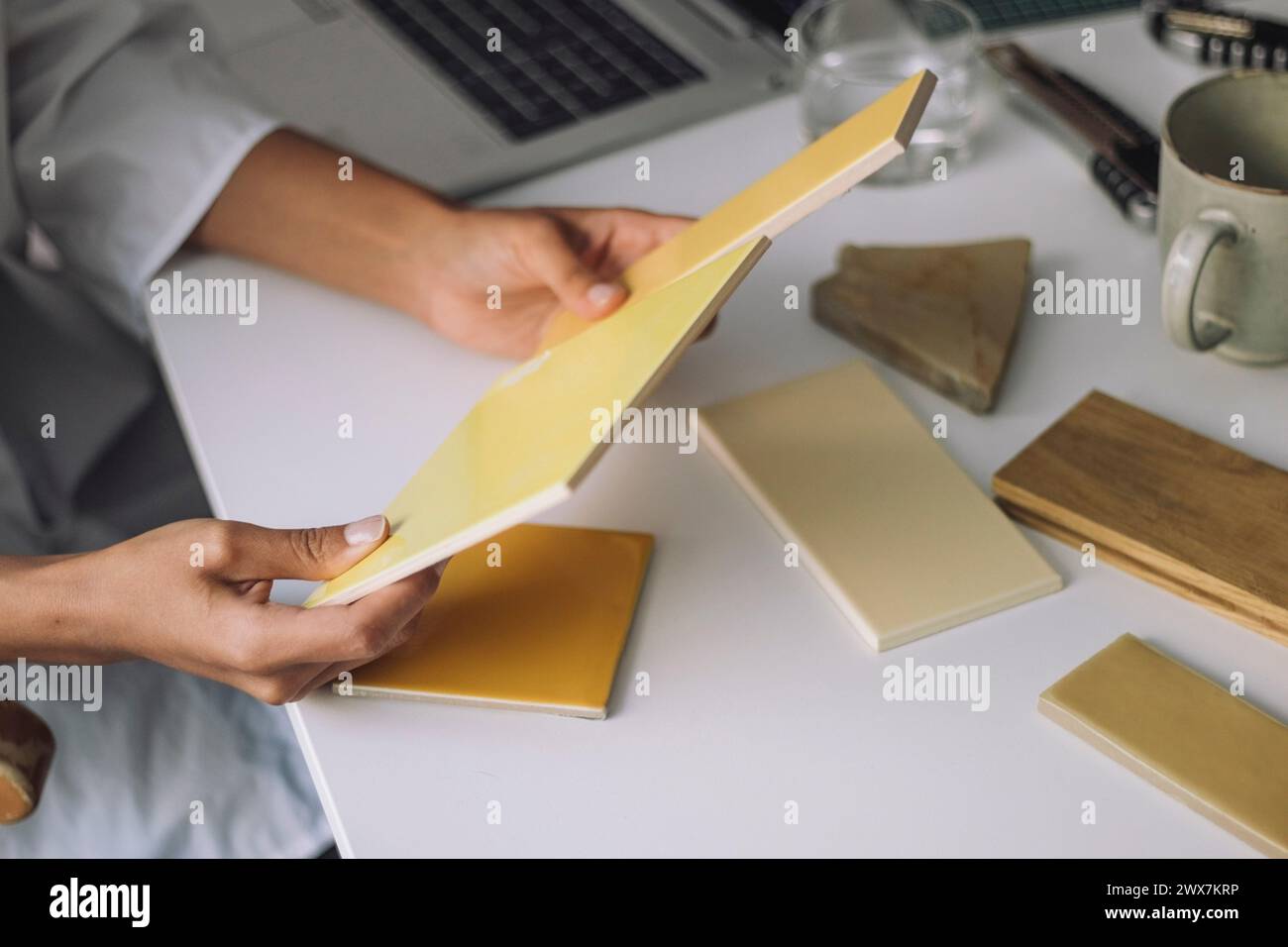 Hands of female architect comparing color samples while sitting at desk in office Stock Photo