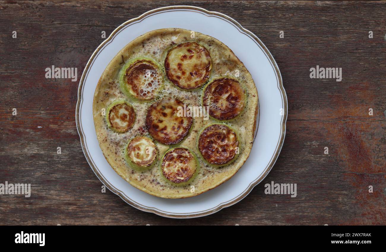 Delicious omelet with zucchini squash. It is located on a wooden surface. Close-up. Stock Photo