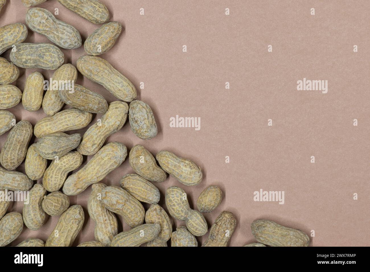 Unshelled peanuts scattered on cardstock background with copy space
