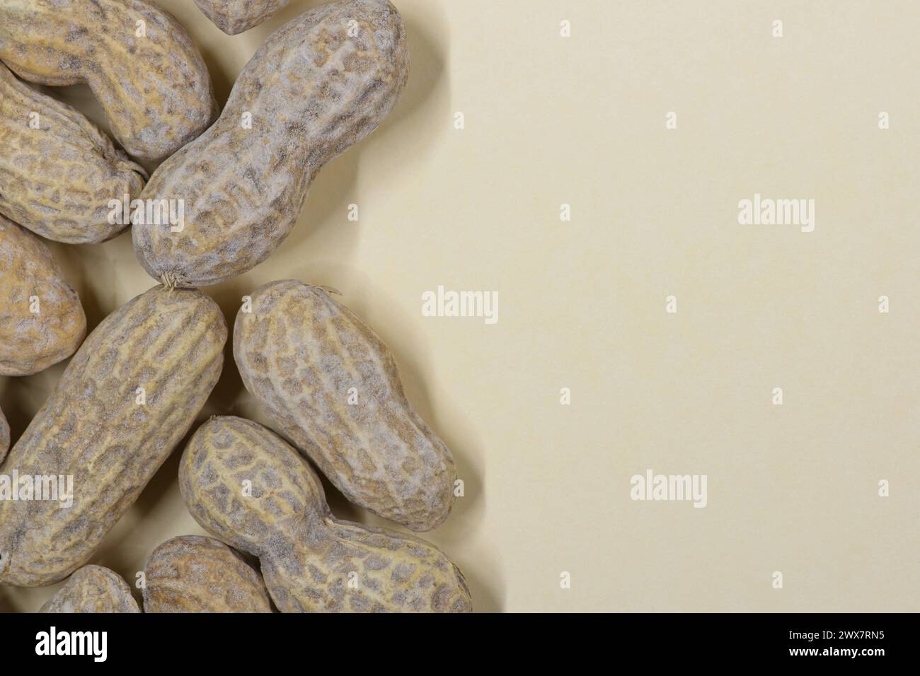 Unshelled peanuts scattered on cardstock background with copy space