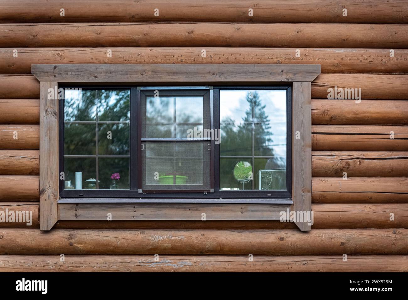 Rectangular window with double glazing on the wall of a log house. From the series Window of the World. Stock Photo