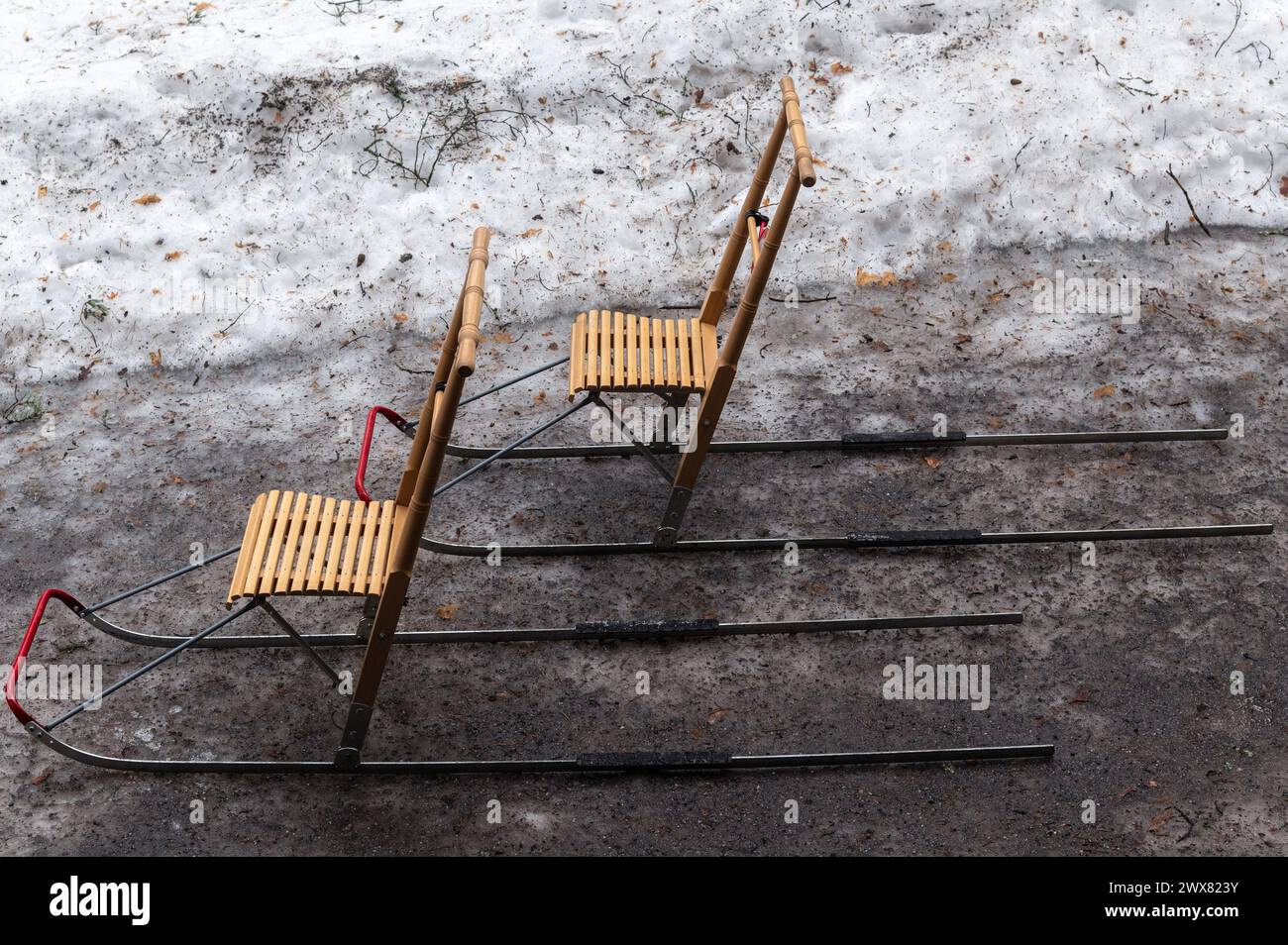 Two Finnish sleighs on a footpath covered with a thin crust of ice, next to a snowdrift. Stock Photo