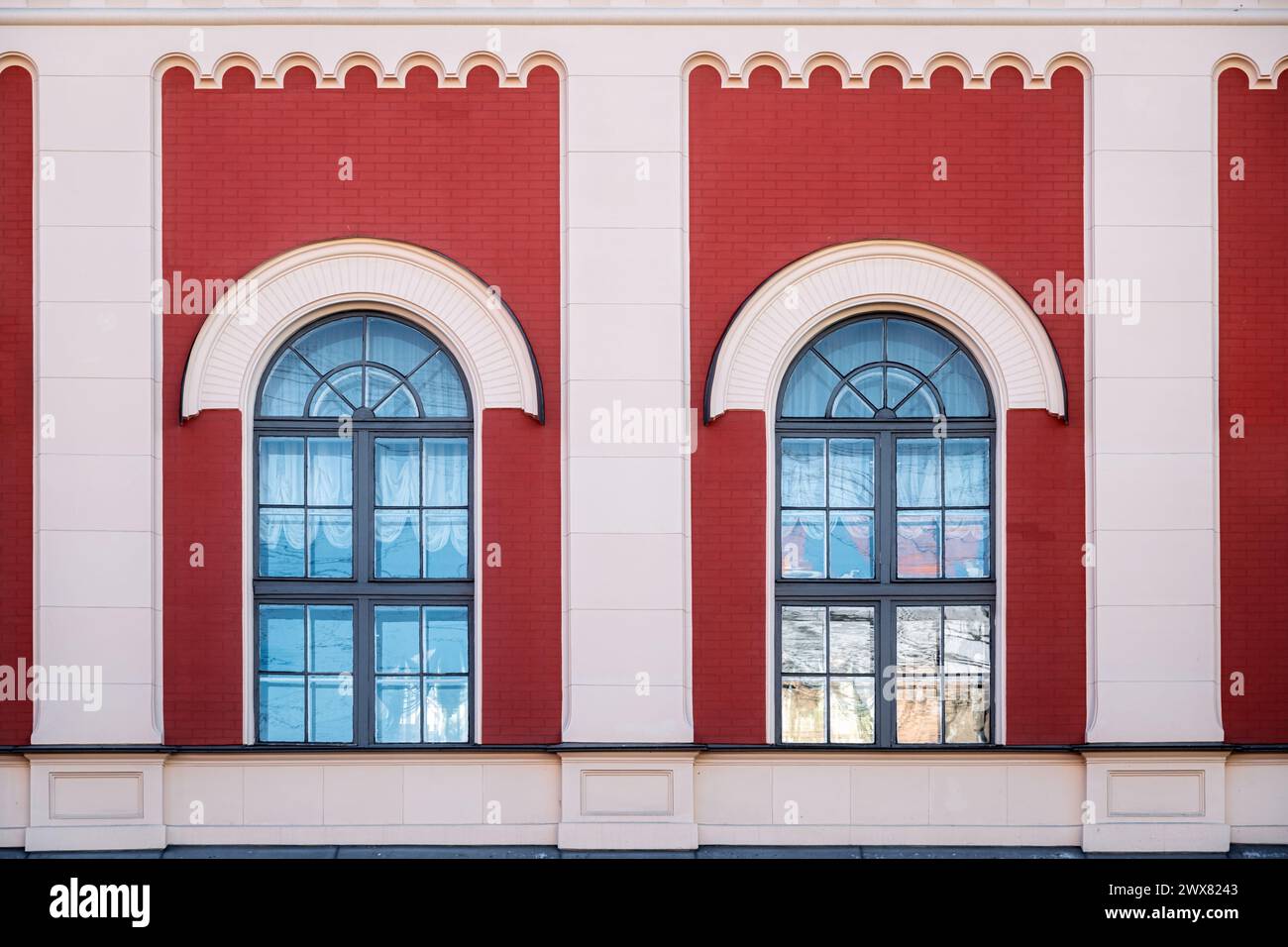 Two arched windows with gray frames against a red brick wall with columns. From the series Window of the World. Stock Photo
