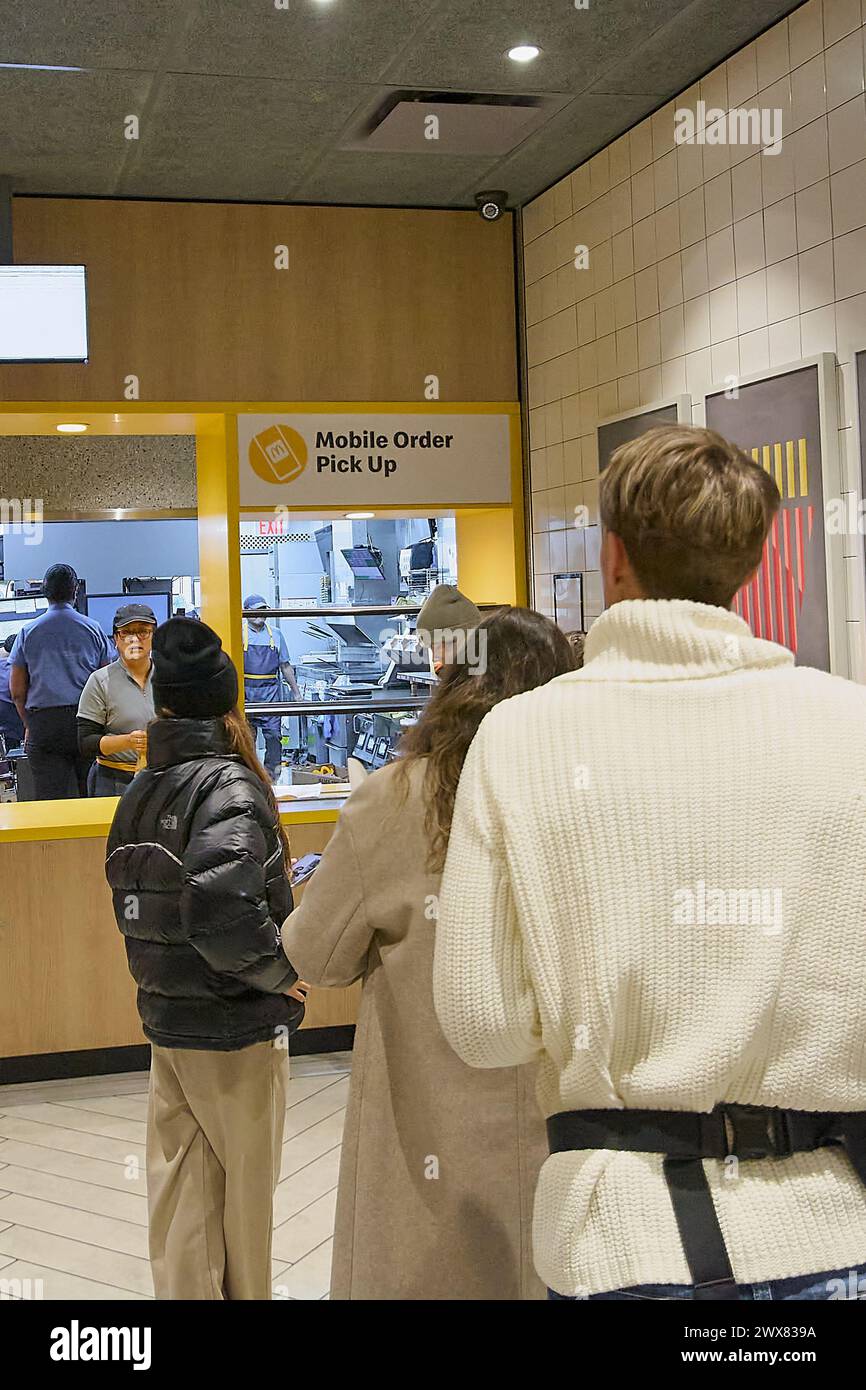 Nueva York, USA - March 27, 2024: Customers in line waiting to pick up their mobile orders at a fast food restaurant, showing an efficient and modern Stock Photo