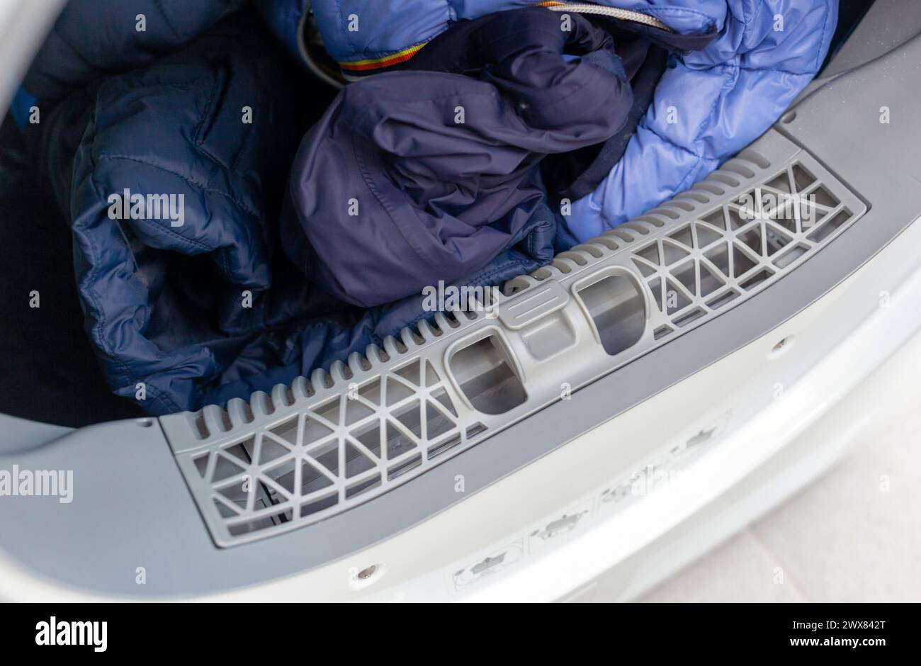 Top view of an open clothes dryer showing a clean lint filter and freshly dried laundry inside Stock Photo
