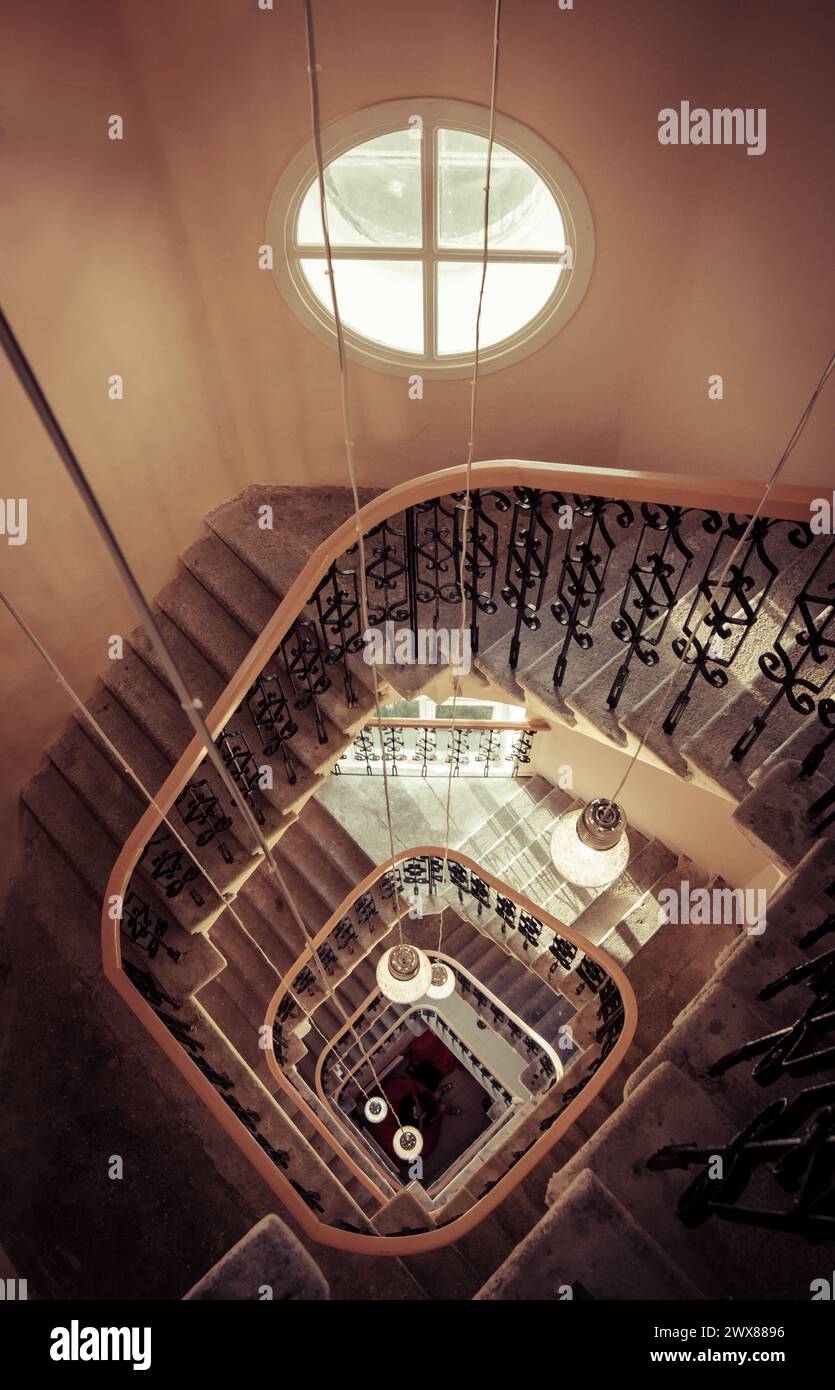 Spiral staircase in tower - view from above. Perspective view of square-shaped staircase in an old house. Orange-brown-ish interior of tower. Stock Photo