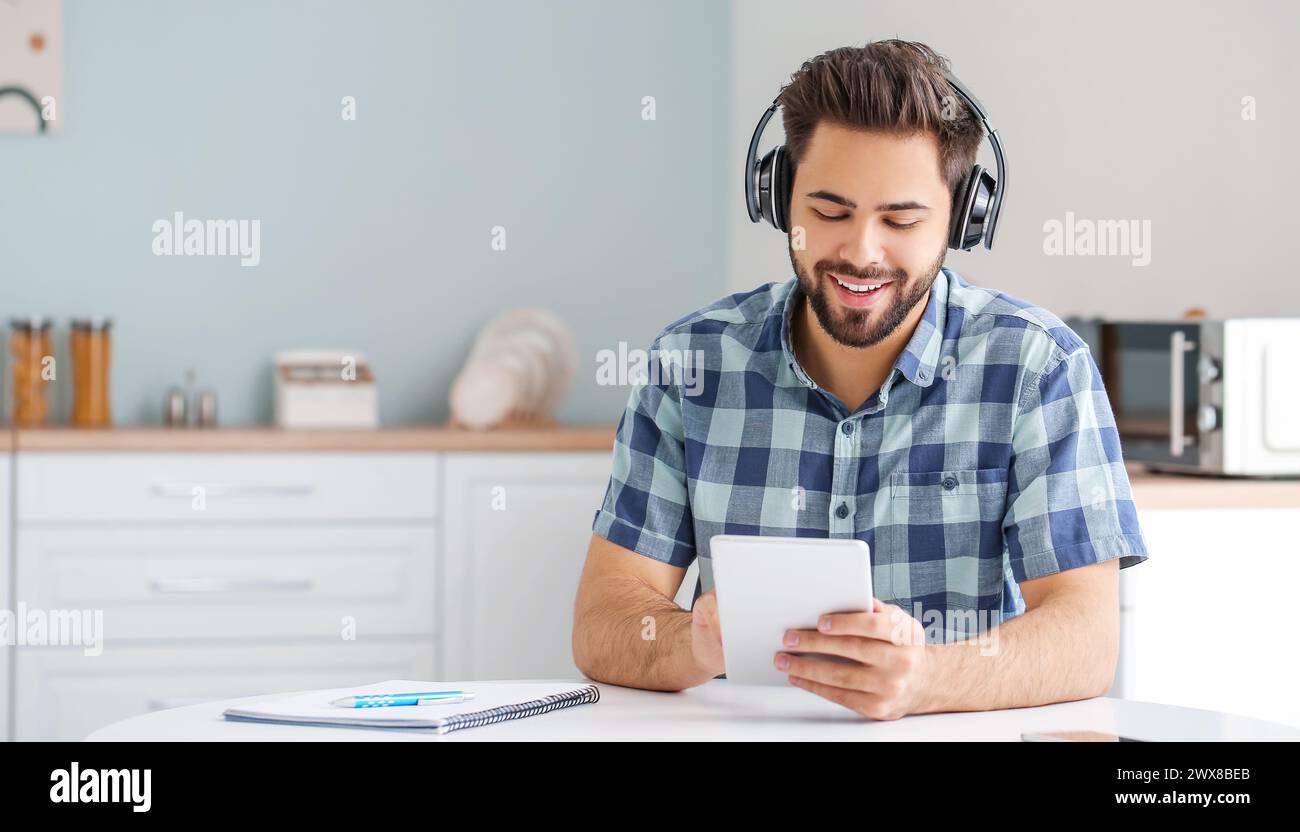 Young man using tablet computer and headphones at home Stock Photo