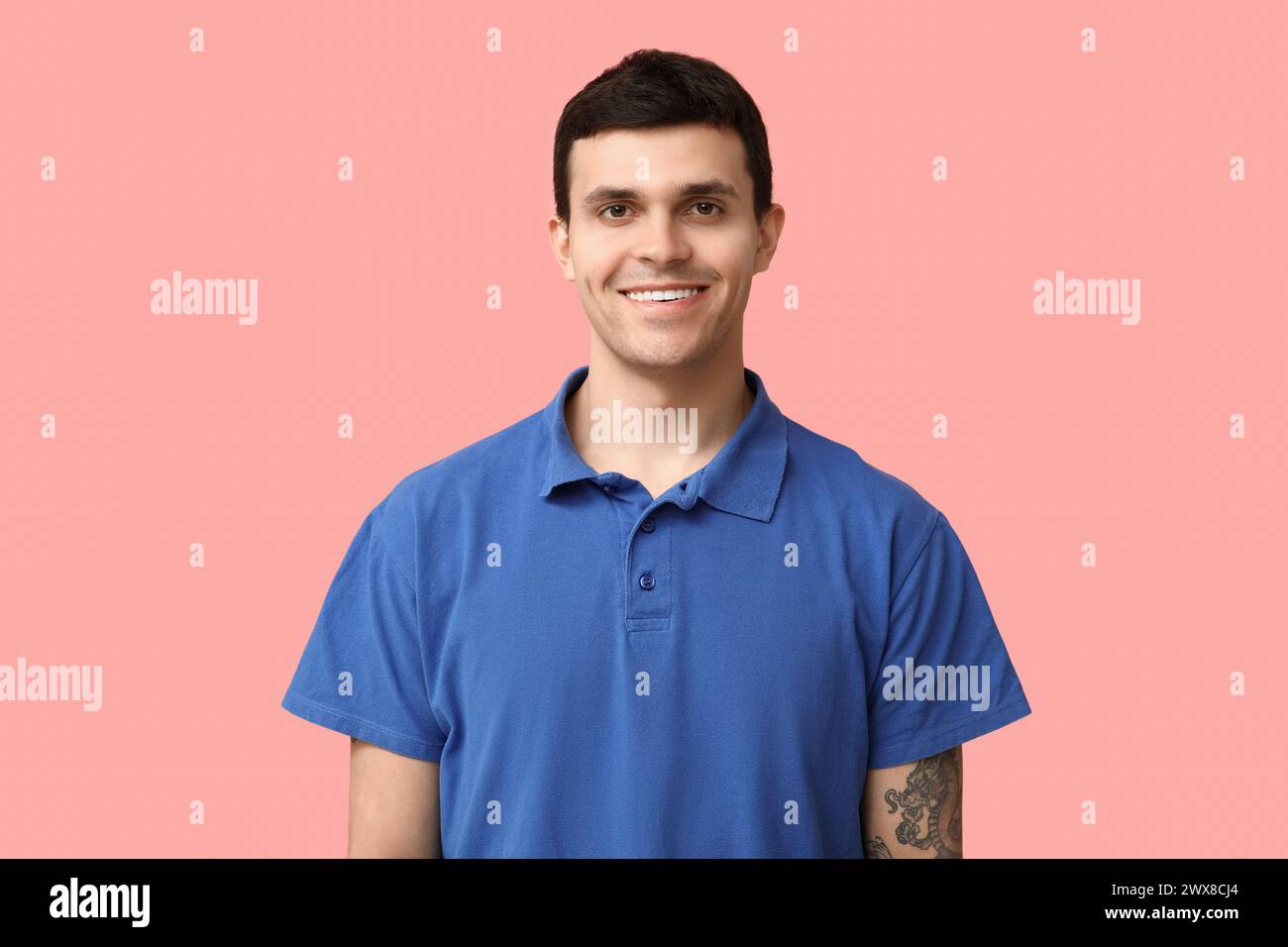 Handsome young man in stylish blue t-shirt on pink background, closeup Stock Photo