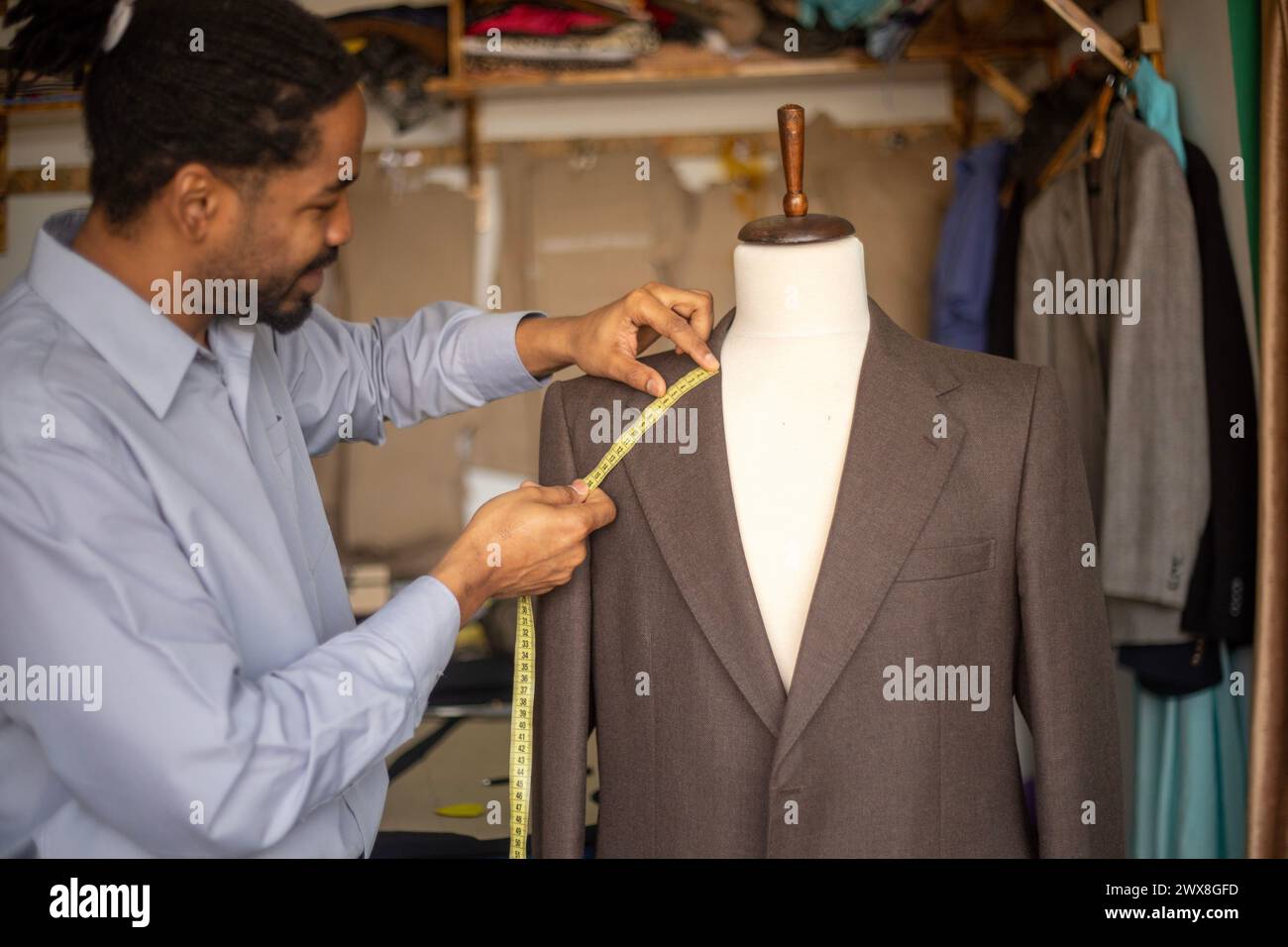 Young African American tailor at work measuring and marking jacket collar, Bespoke tailor at work Stock Photo