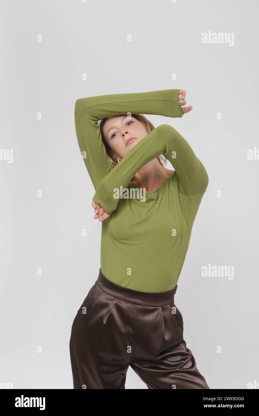 Serie of studio photos of young female model wearing comfortable basic outfit, green viscose fitted shirt and brown trousers Stock Photo