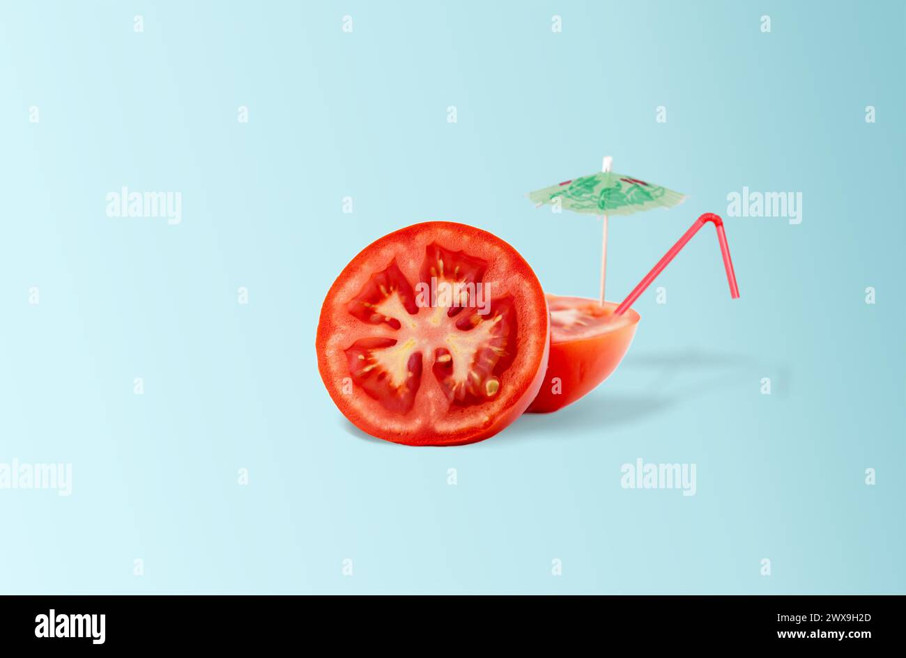 Tomato cocktail with straw and sun umbrella on light blue gradient background. Minimal summer tropical beach concept Stock Photo