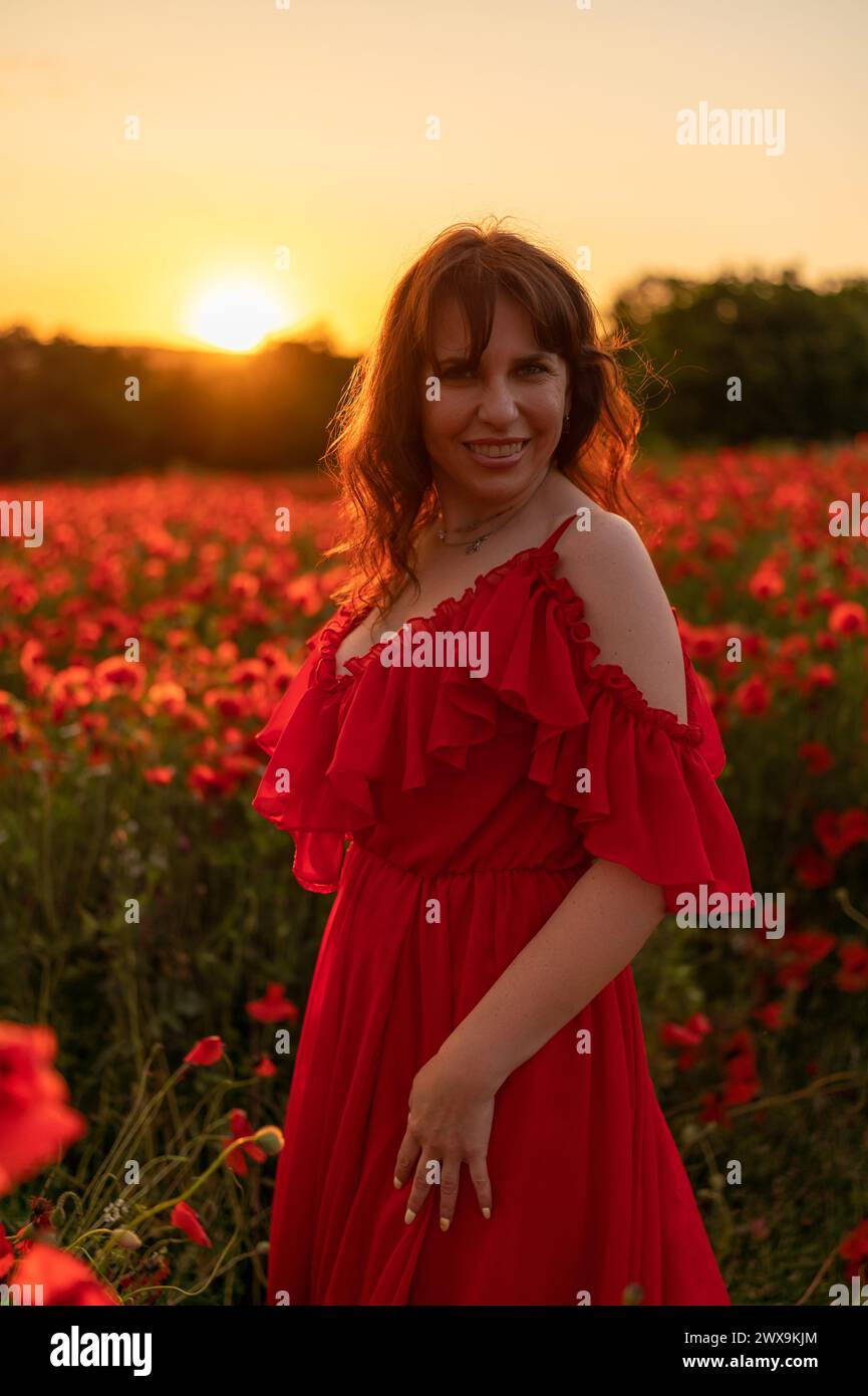 Woman poppy field red dress sunset. Happy woman in a long red dress in ...