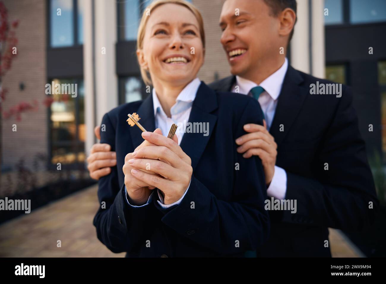 Man embraces woman who holds keys in hands Stock Photo