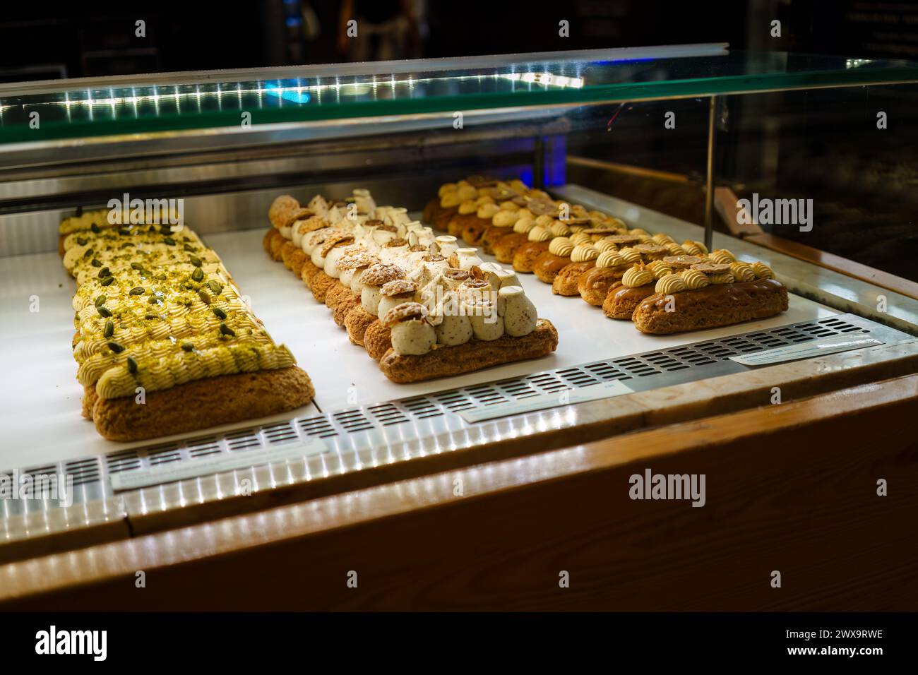 Rows of crafted pastries in a bakery display case Stock Photo