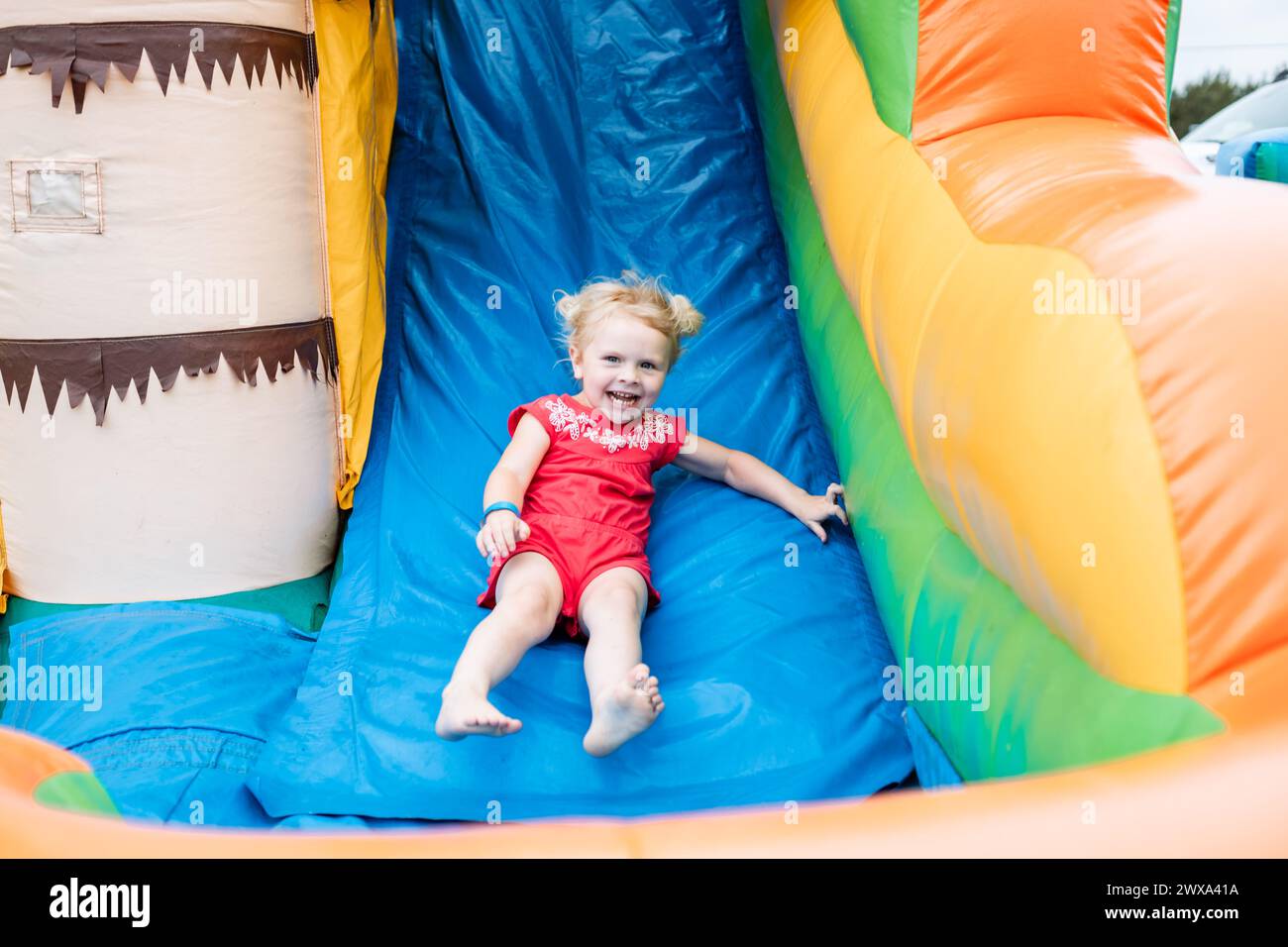Laughing young girl sliding down inflatable bounce slide Stock Photo ...