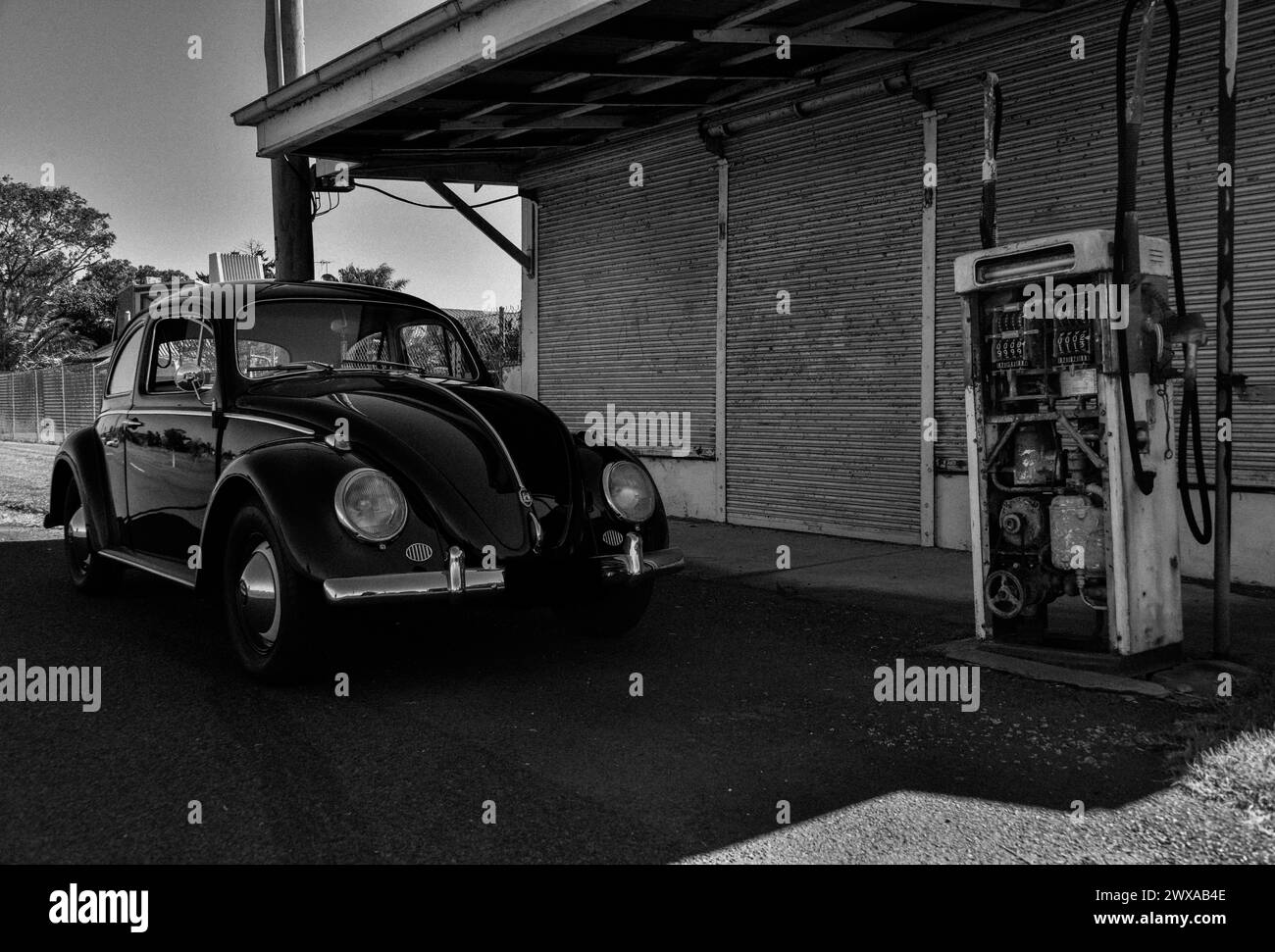 Classic VW Volkswagen Beetle Black White in front of an old service station garage fuel pump bowser. The 'Black Bug' Stock Photo