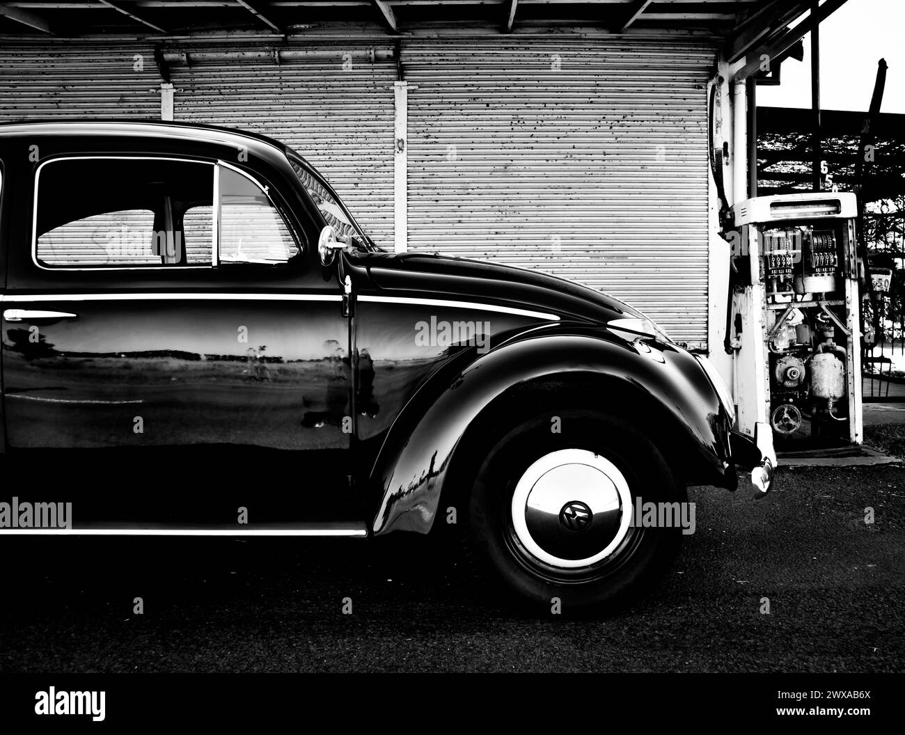 Classic VW Volkswagen Beetle Black White in front of an old service station garage fuel pump bowser. The 'Black Bug' Stock Photo