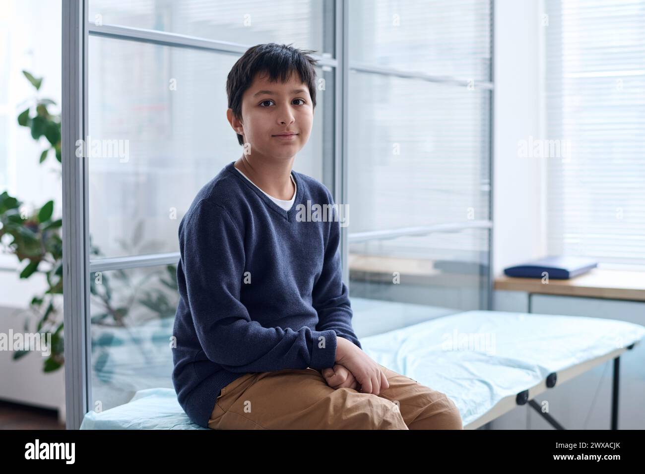 Portrait of young Middle Eastern boy sitting on cot in medical clinic