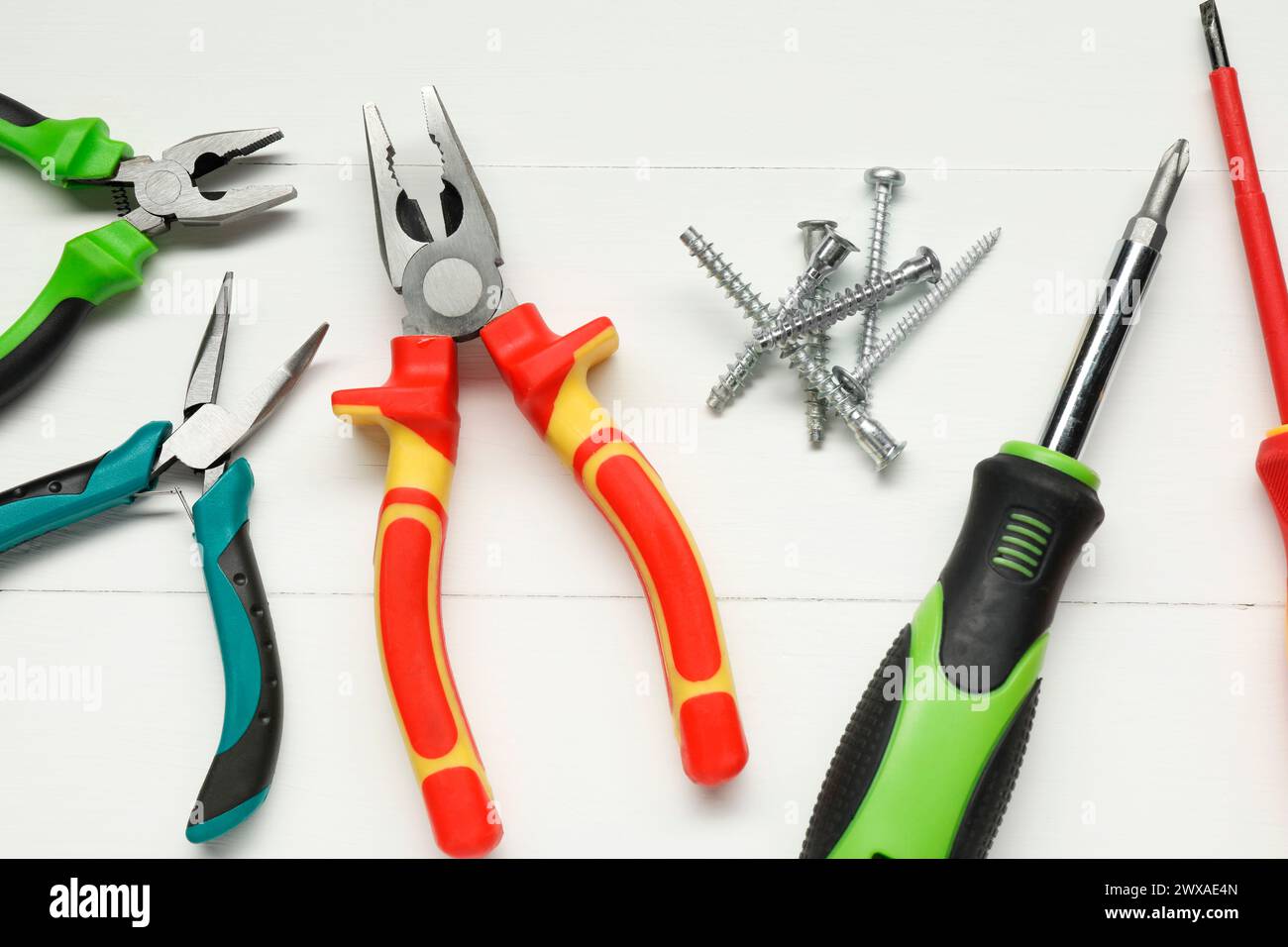 Pliers, screwdrivers and screws on white wooden table, flat lay Stock Photo