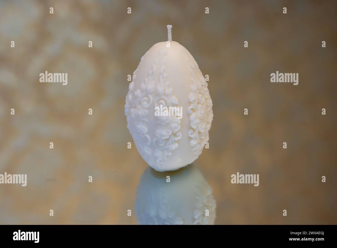 White easter egg soy wax candle. Mirror background Stock Photo