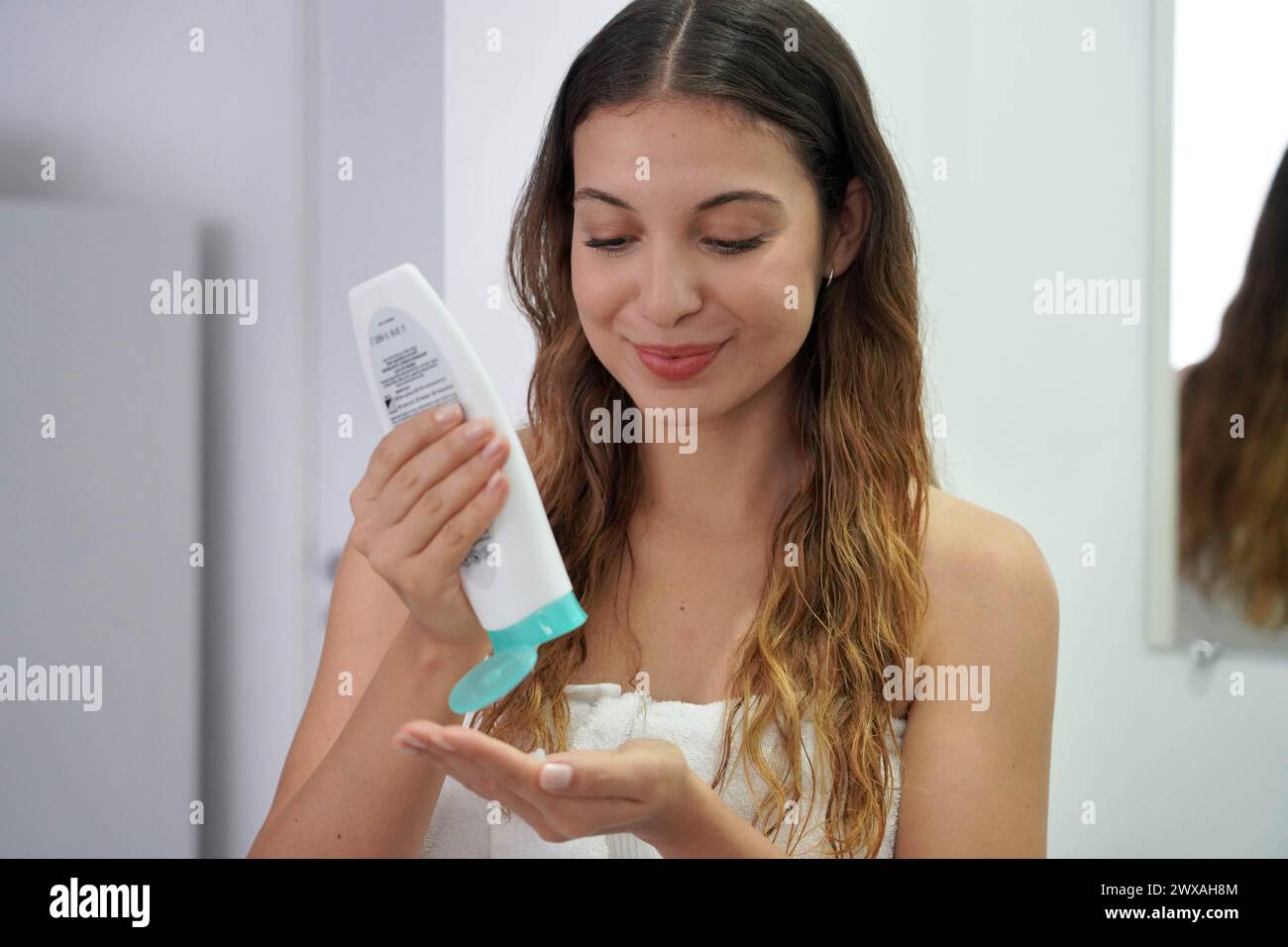 Anti-frizz leave-in conditioner. Beautiful young woman using hair thermal protection. Cream heat protectant. Stock Photo