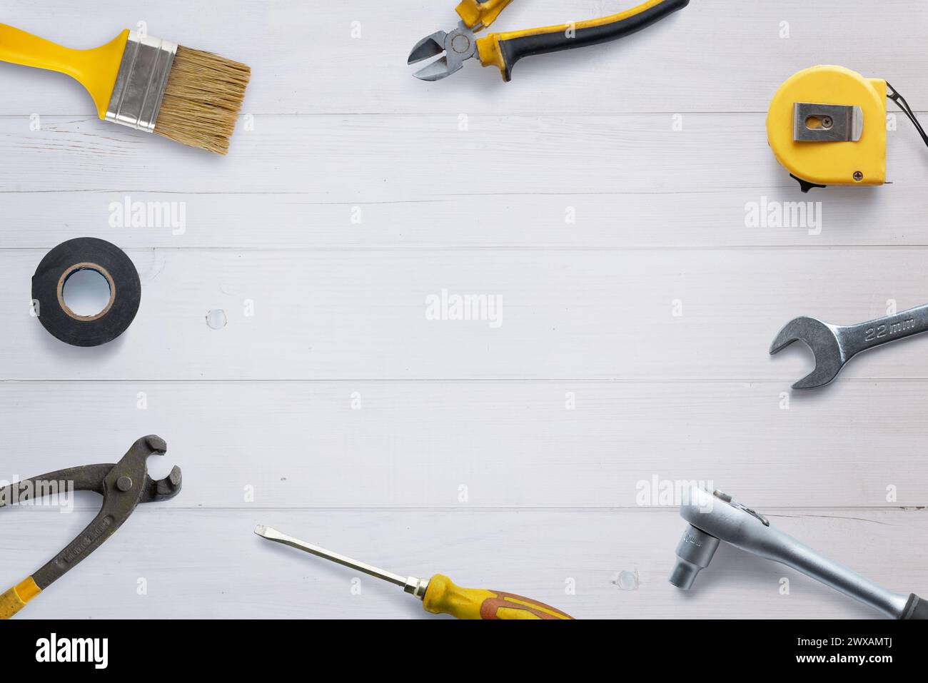 Top view of assorted tools neatly arranged on a white wooden desk, with copy space in the center. Flat lay composition ideal for DIY concept promotion Stock Photo