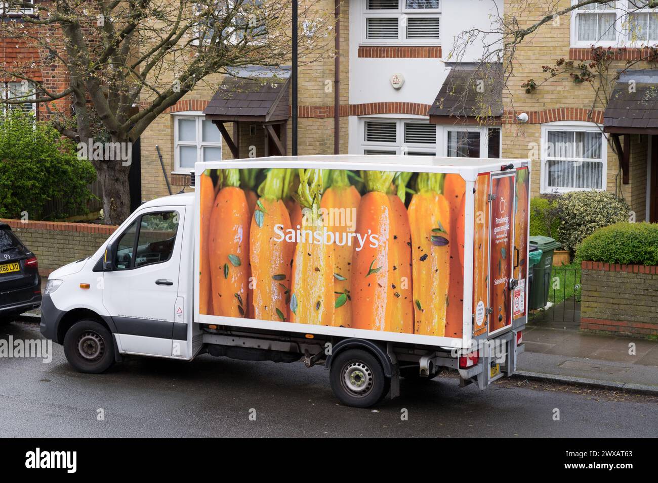 offside rear view of a Sainsbury's home delivery van park outside a residential terrace houses in London England UK Stock Photo