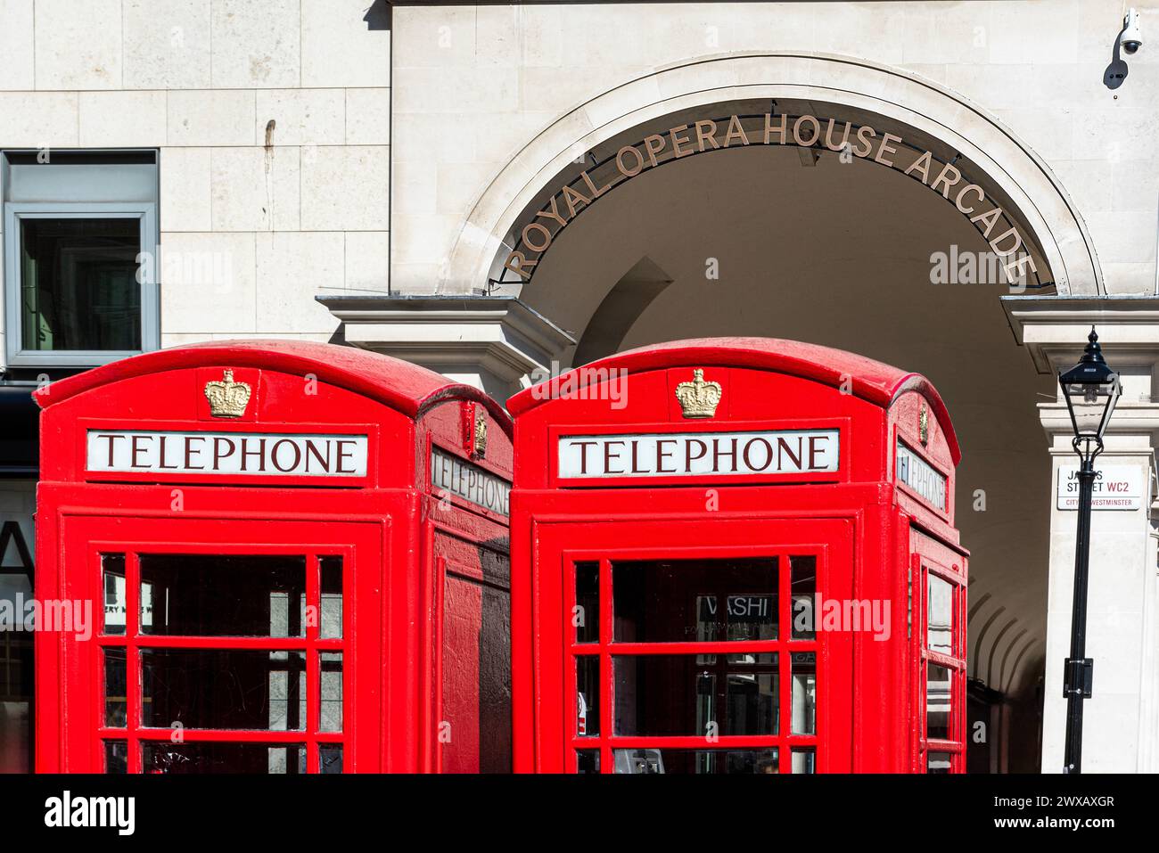 Red  Telephone Boxes outside of Entrance to the Royal Opera House Arcade with the entrance sign, Covent Garden, London in the sunshine. Stock Photo