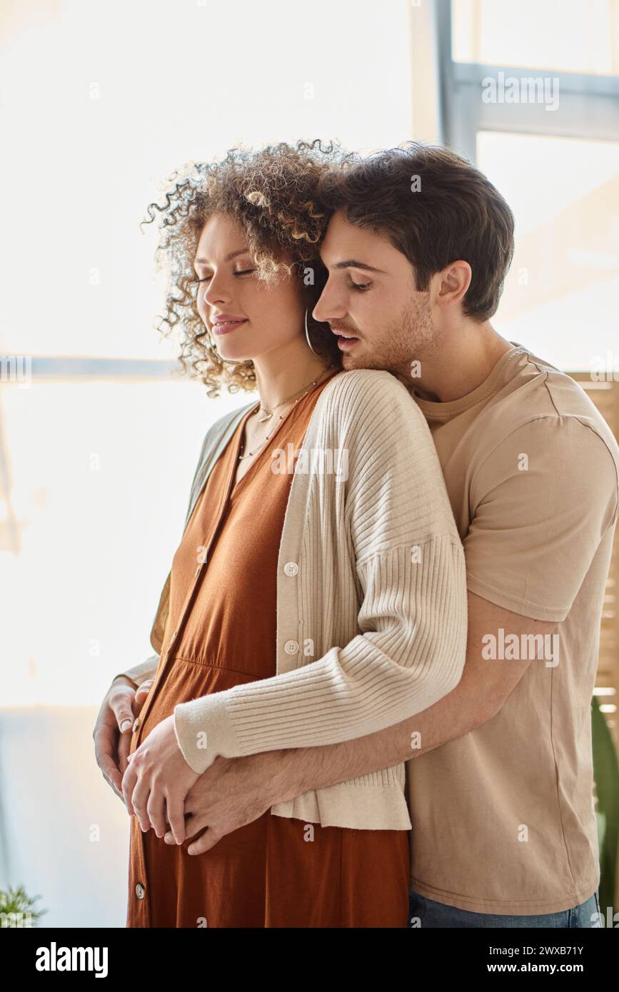 Expecting baby couple, man hugging his pregnant wife from behind ...
