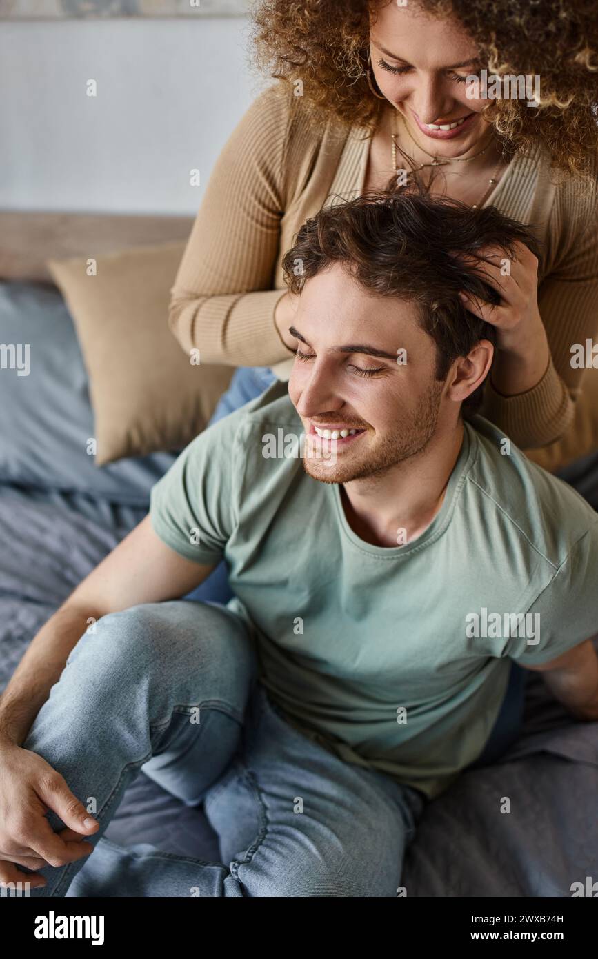 curly young woman massaging boyfriends head cherishing their moment together Stock Photo