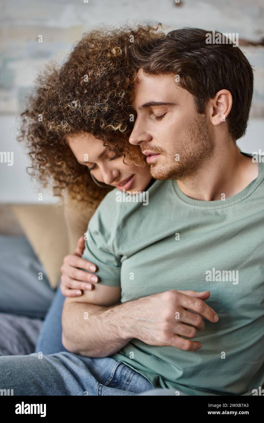 curly young woman and brunette man savor a warm hug, cherishing the quiet moment Stock Photo