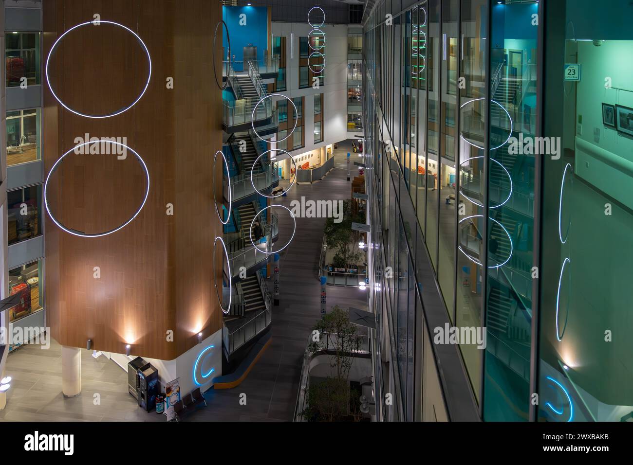 Elevated view of a spacious, well-lit corporate building interior with artistic light fixtures after hours Stock Photo