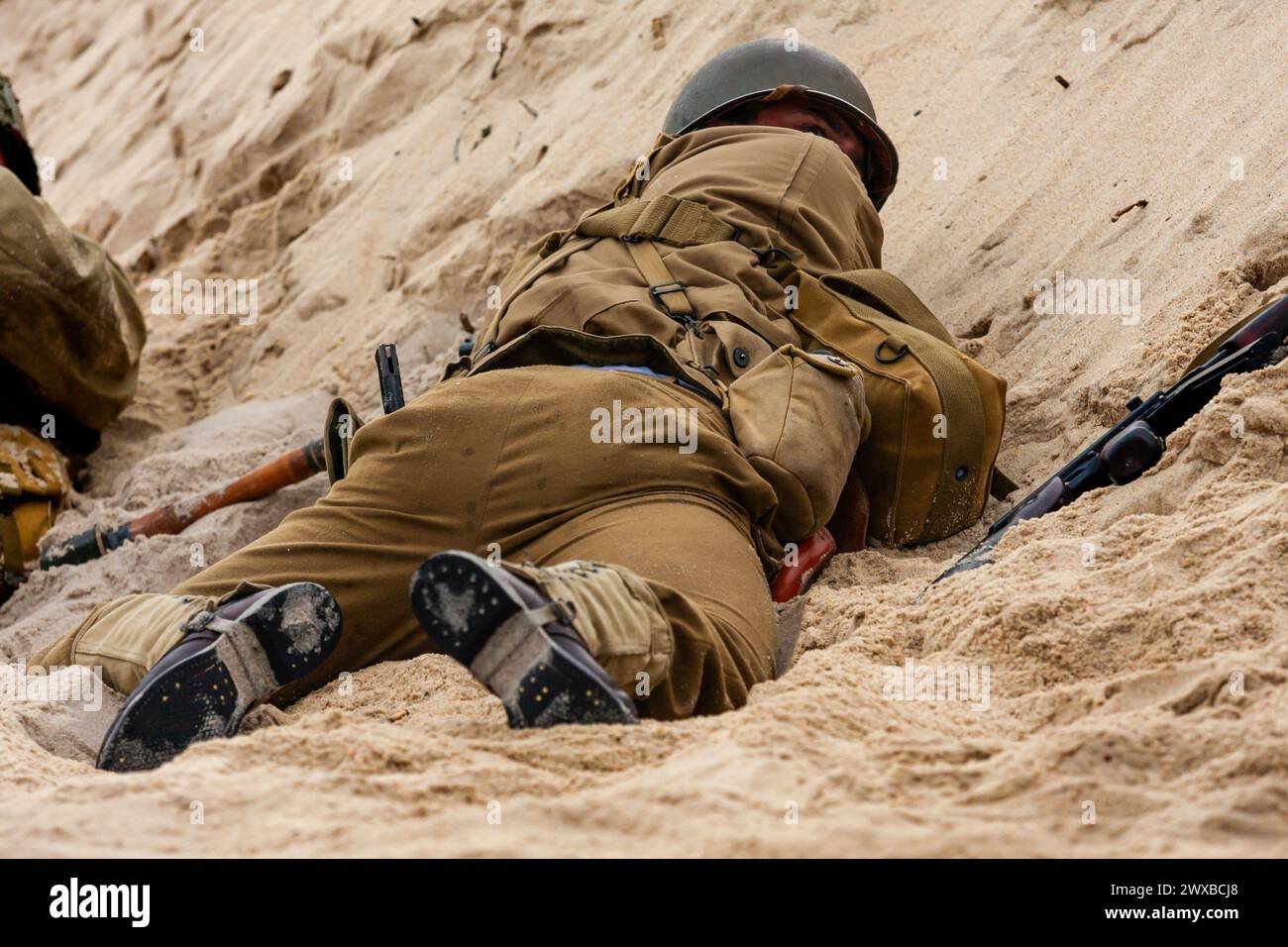 Historical reconstruction. An American infantry soldier from the World War II  fighting on the beach. View from the back. Stock Photo