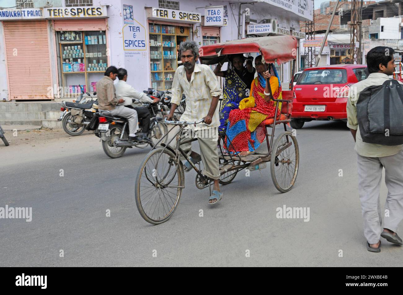 A cycle rickshaw transports passengers on a busy street in a city, Jaipur, Rajasthan, India Stock Photo