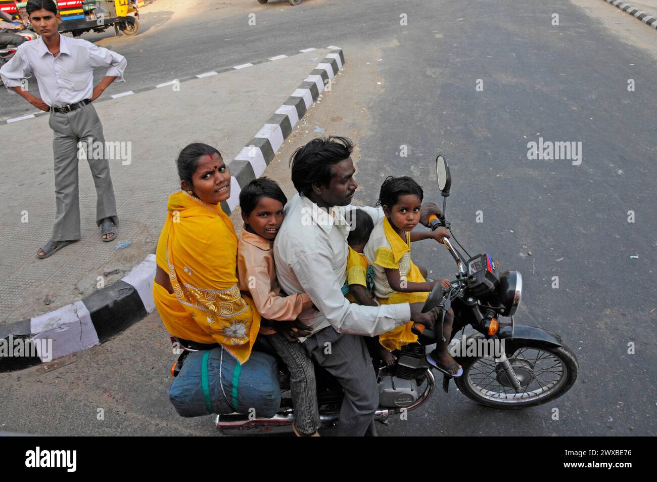 An Indian family rides together on a motorbike through an urban environment, Rajasthan, India Stock Photo