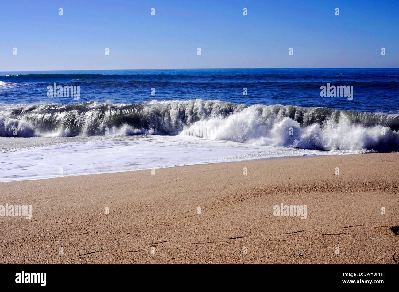 A wave breaks on a sandy beach with visible footprints in the foreground, near Vila Cha, Porto, Northern Portugal, Portugal Stock Photo