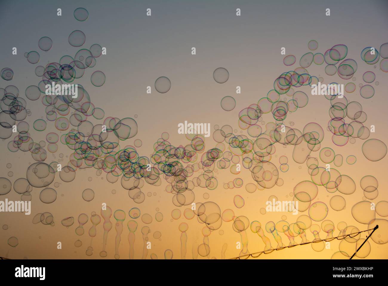 Lots of colorful soap bubbles floating in the orange sky at sunset with ...
