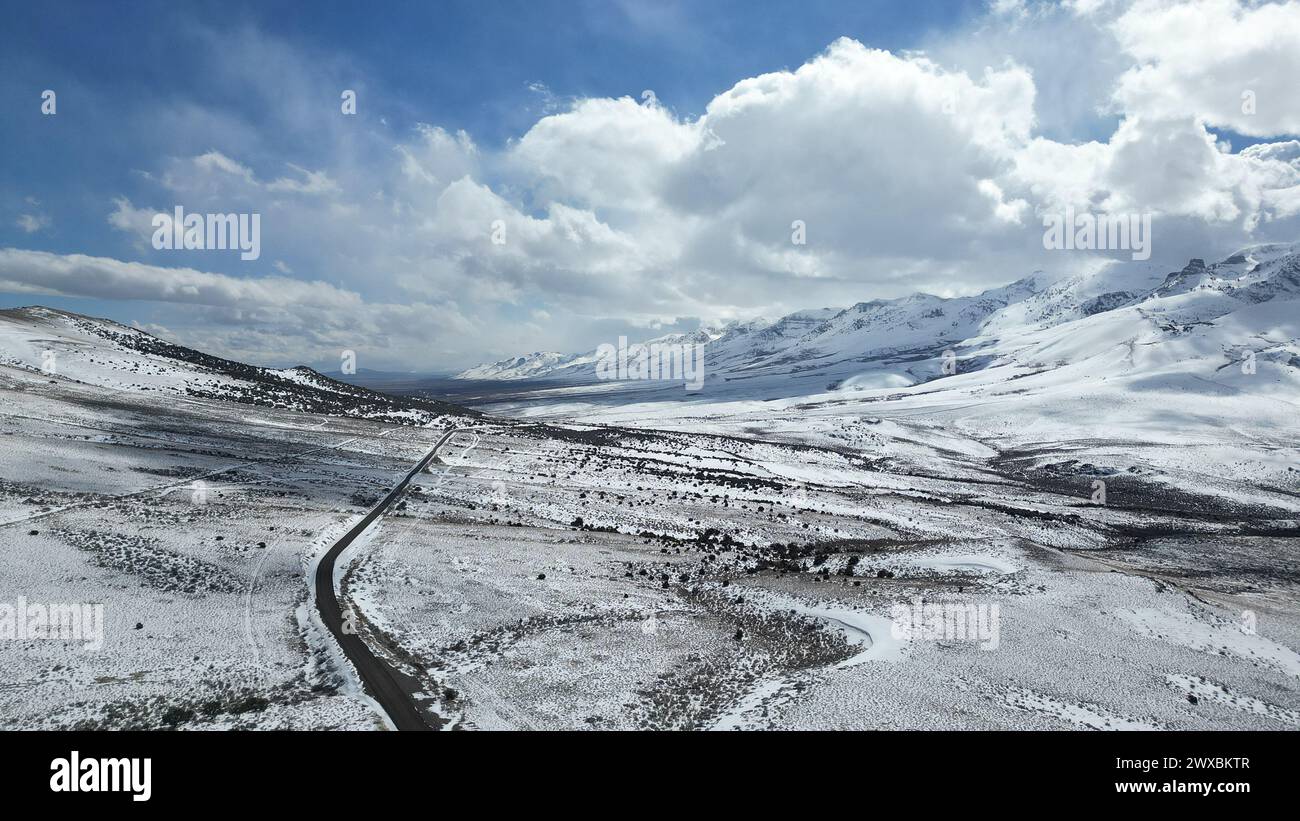 Snow-covered road winding through a valley with no traffic Stock Photo