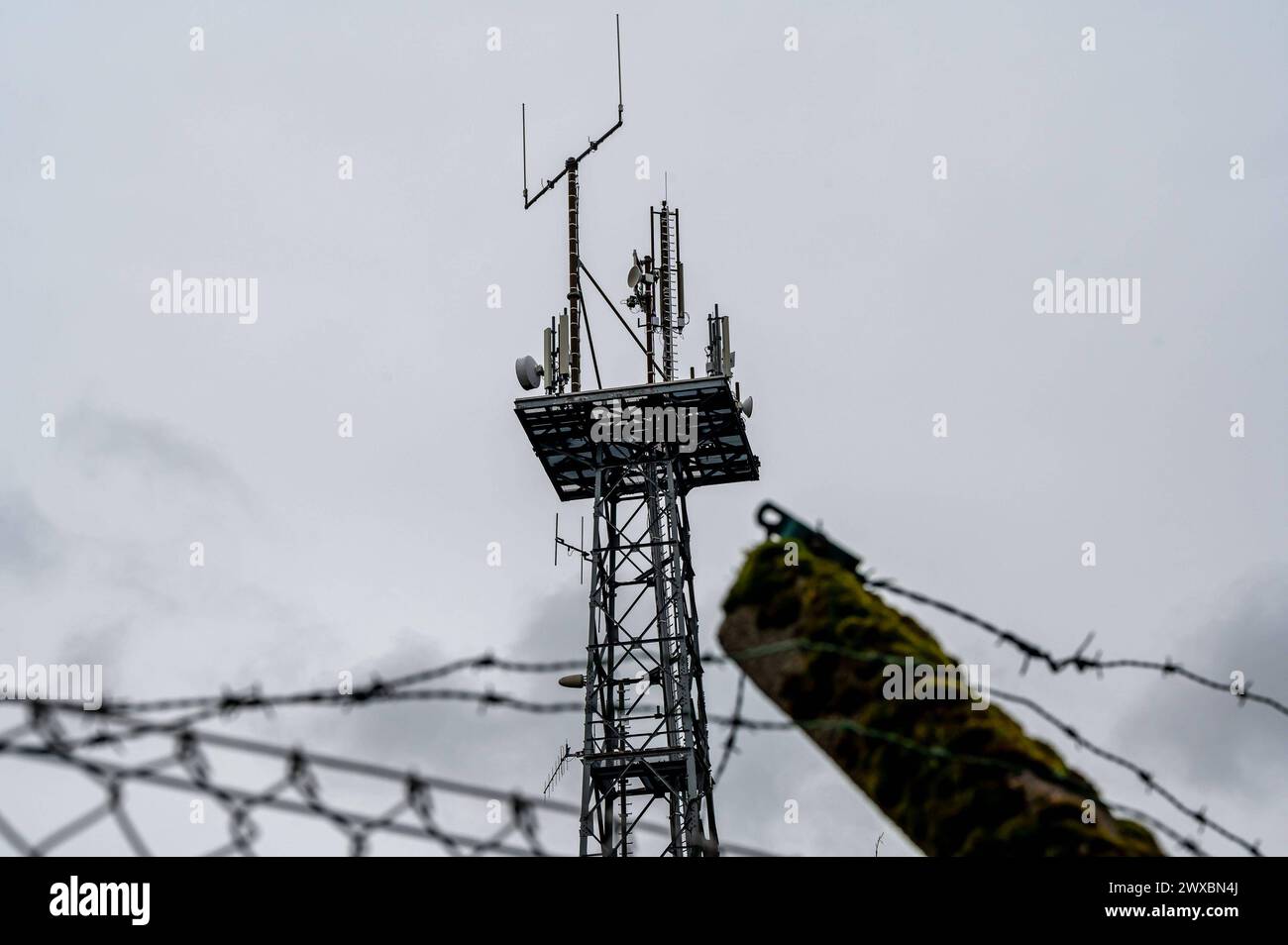 Mobillfunksender auf Sendemast des ehemaligen Warnamtes Meinerzhagen Im Zuge der Auflösung im Jahre 1997 wurde auch das Warnamt Meinerzhagen Märkischer Kreis, Sauerland stillgelegt. Auf dem Anwesen sind mittlerweile Privatfirmen angesiedelt. Der Sendemast wird weiter artgerecht genutzt und beherbergt Richtfunkstrecken und Mobilfunkantennen. Das Gelände ist noch immer gut gesichert: Aufgrund der Funktion der Warnämter während des Kalten Krieges ist die Liegenschaft ähnlich wie eine Kaserne oder eine Grenzanlage gesichert: Mit Stacheldraht und hohen Zäunen. Für Unbefugte ist das Grundstück noch Stock Photo