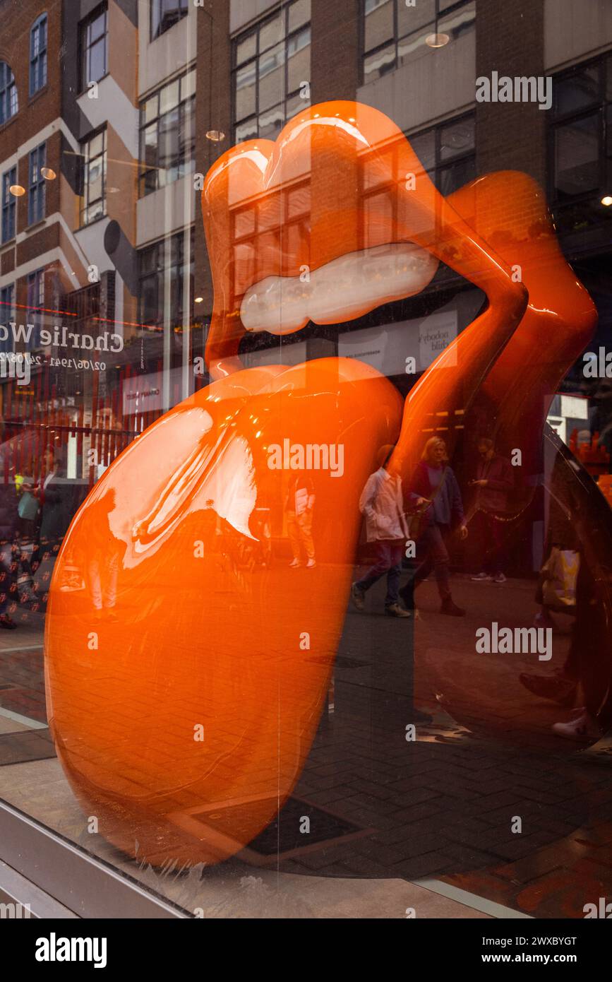 The Rolling Stones iconic lips and tongue logo sculpture looks out from the shop window of  RS No. 9 Carnaby, the legendary rock bands flagship store. Stock Photo