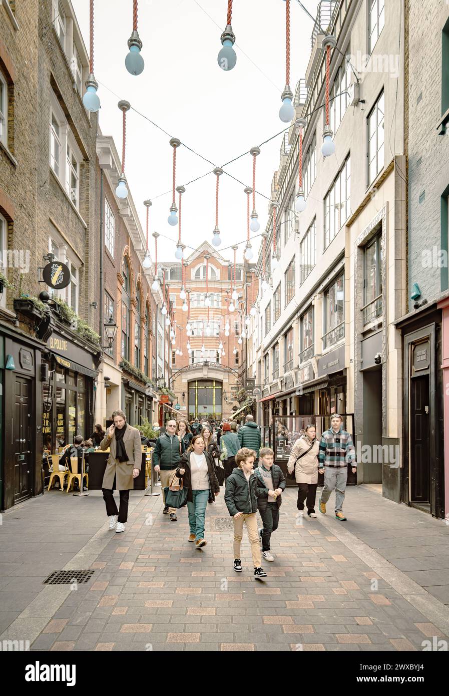 51 large light bulbs float above Ganton Street, forming a permanent art installation while the people below have fun and savor food and drinks. Stock Photo