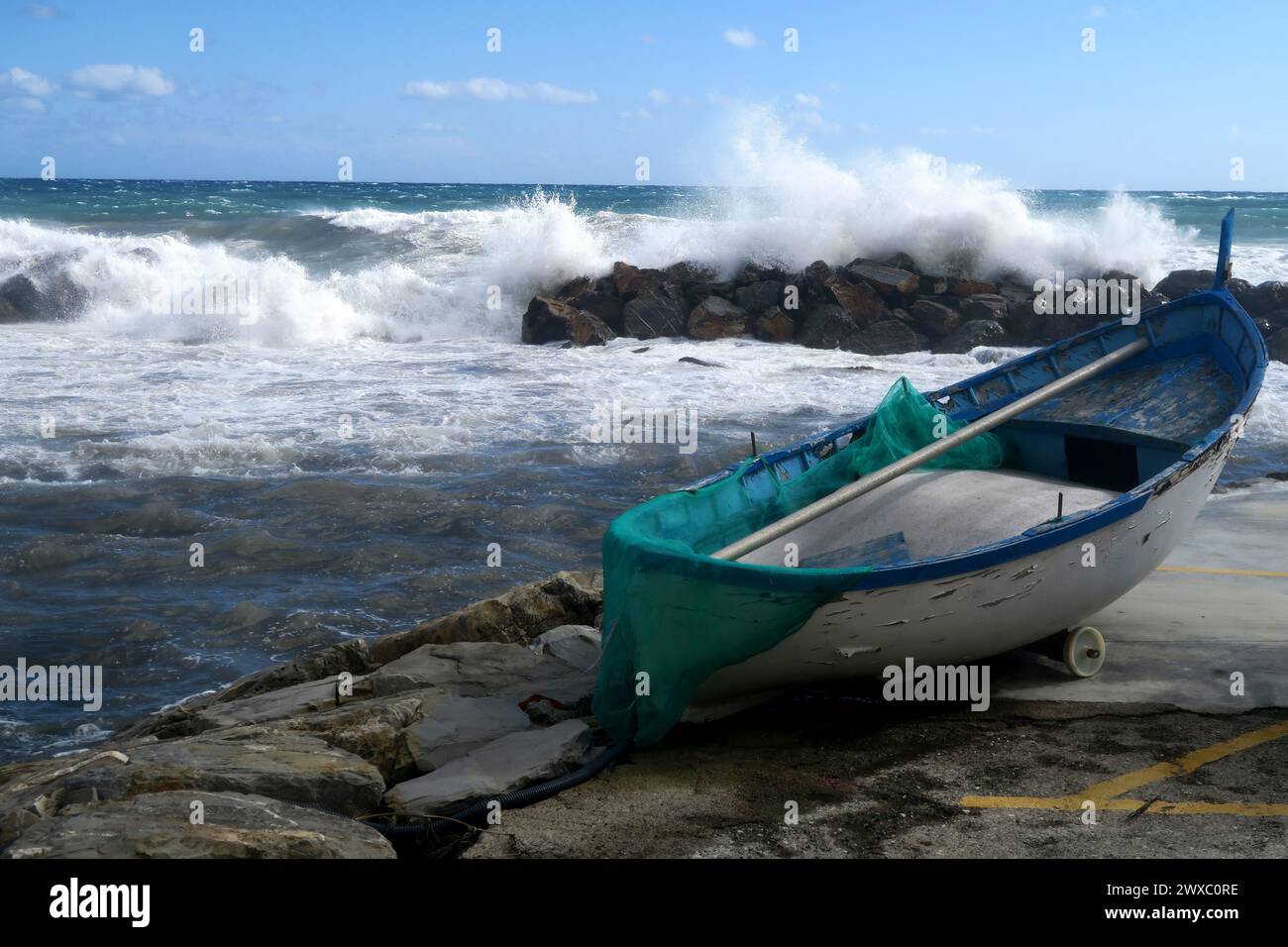 A small boat moored to a dock by the sea Stock Photo