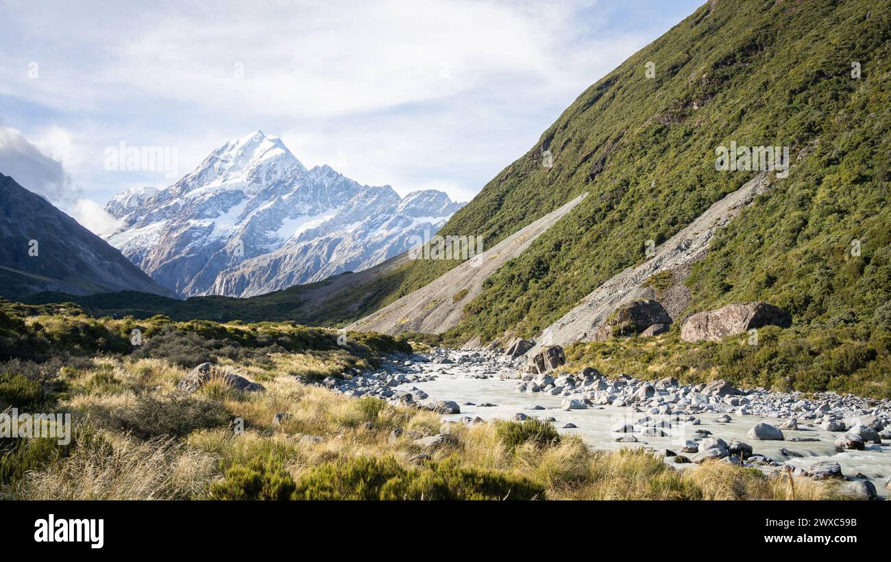 Scenic alpine valley with glacial river flowing through and prominent peak in backdrop, New Zealand. Stock Photo