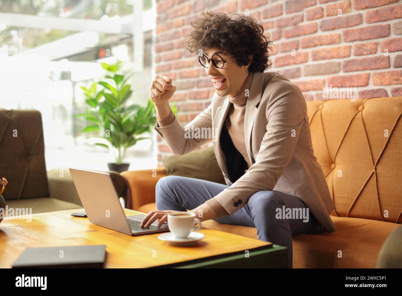Happy young man sitting in a cafe and using a laptop computer Stock Photo