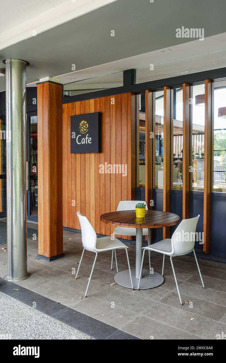 An inviting outdoor cafe setting at Circular Quay, Sydney, features an empty table with three sleek white chairs Stock Photo