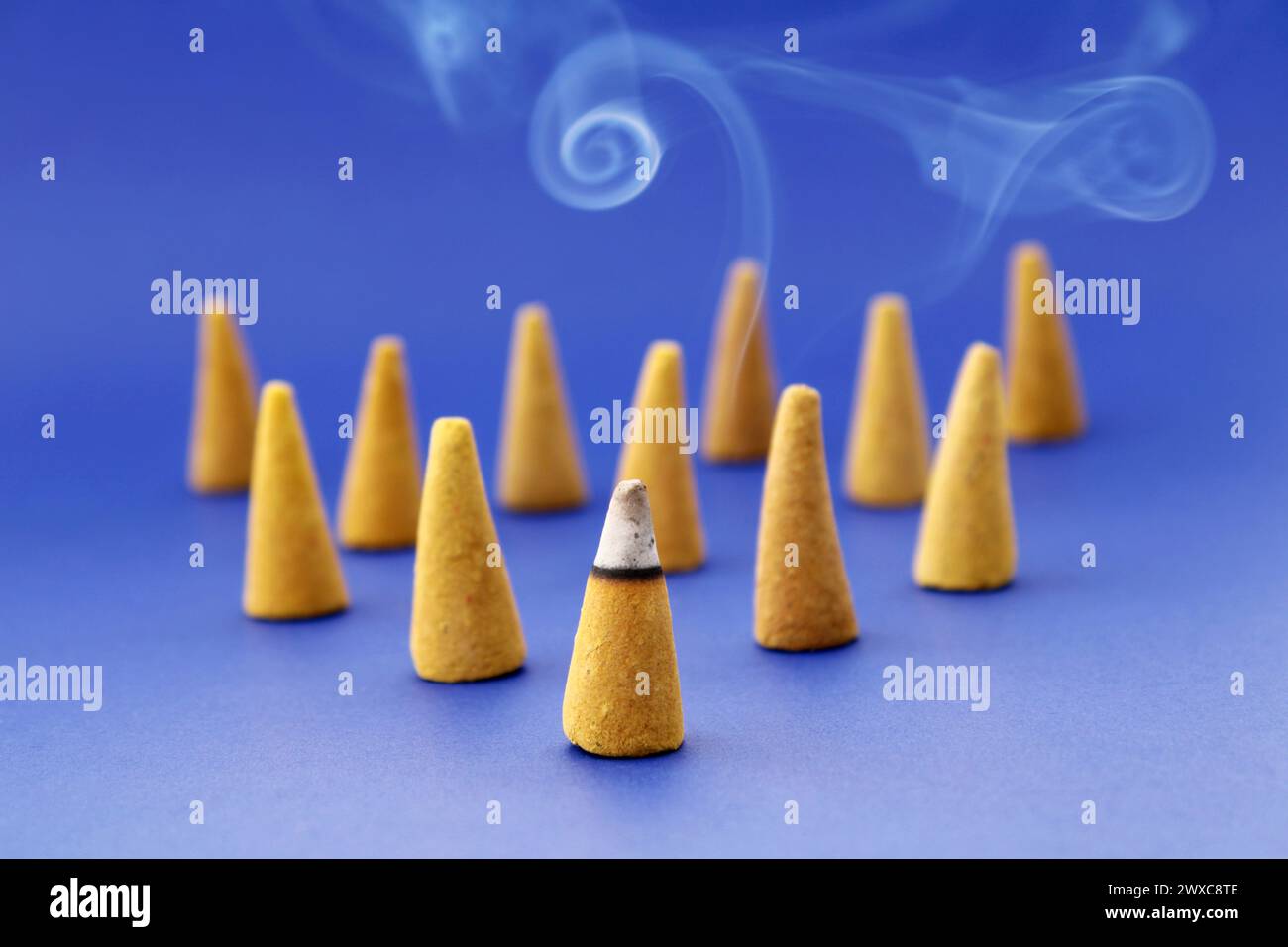 Cone shaped incenses with one of them burning in front Stock Photo