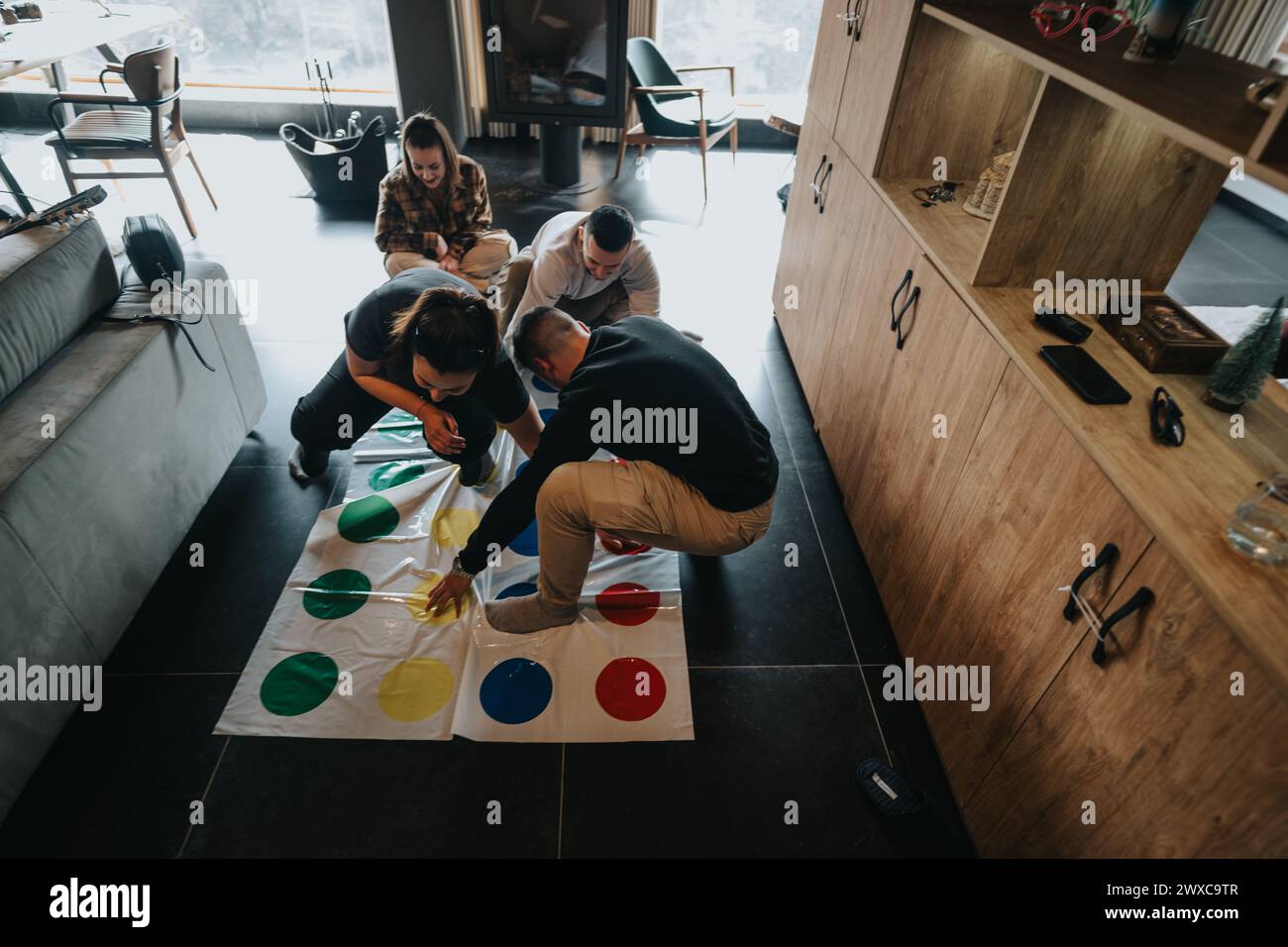 Friends playing Twister game in cozy home environment, fun and leisure concept Stock Photo